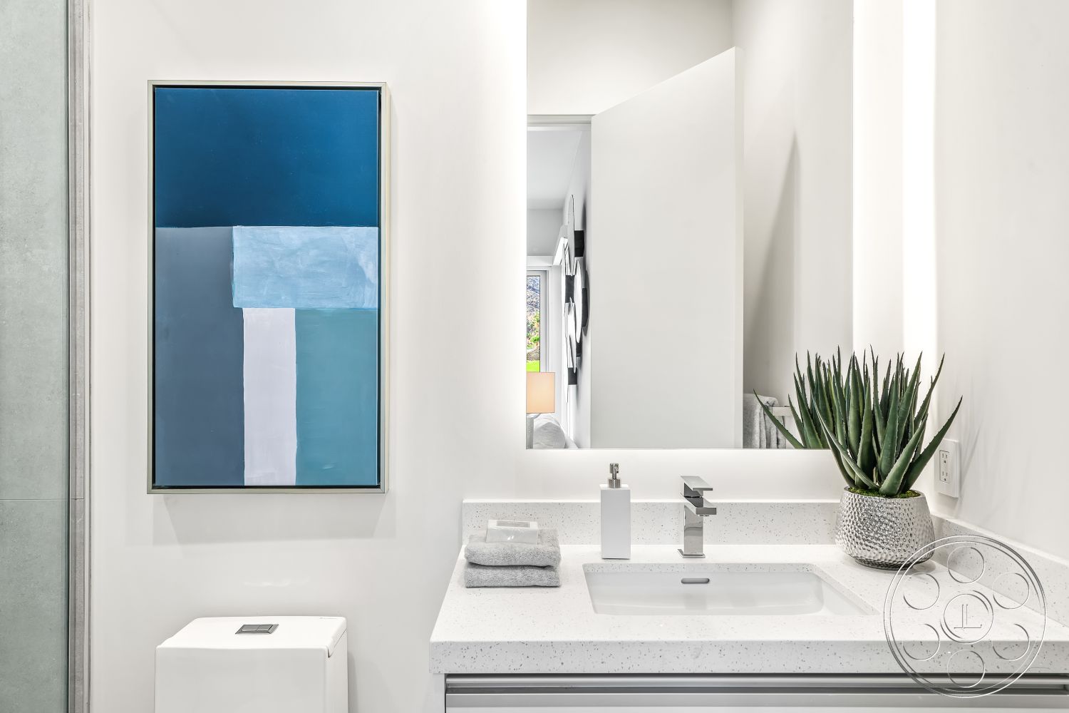Palm Springs 109 - neutral color palette, ceramic tile flooring, minimalist bathroom design, white painted walls, modern floating sink, chrome bathroom faucet, interior bathroom with quartz countertop, large mirror with integrated lighting, opaque glass shower partition, contemporary artwork on wall, indoor potted aloe plant, efficient space layout, satin-finish cabinetry, understated luxury elements