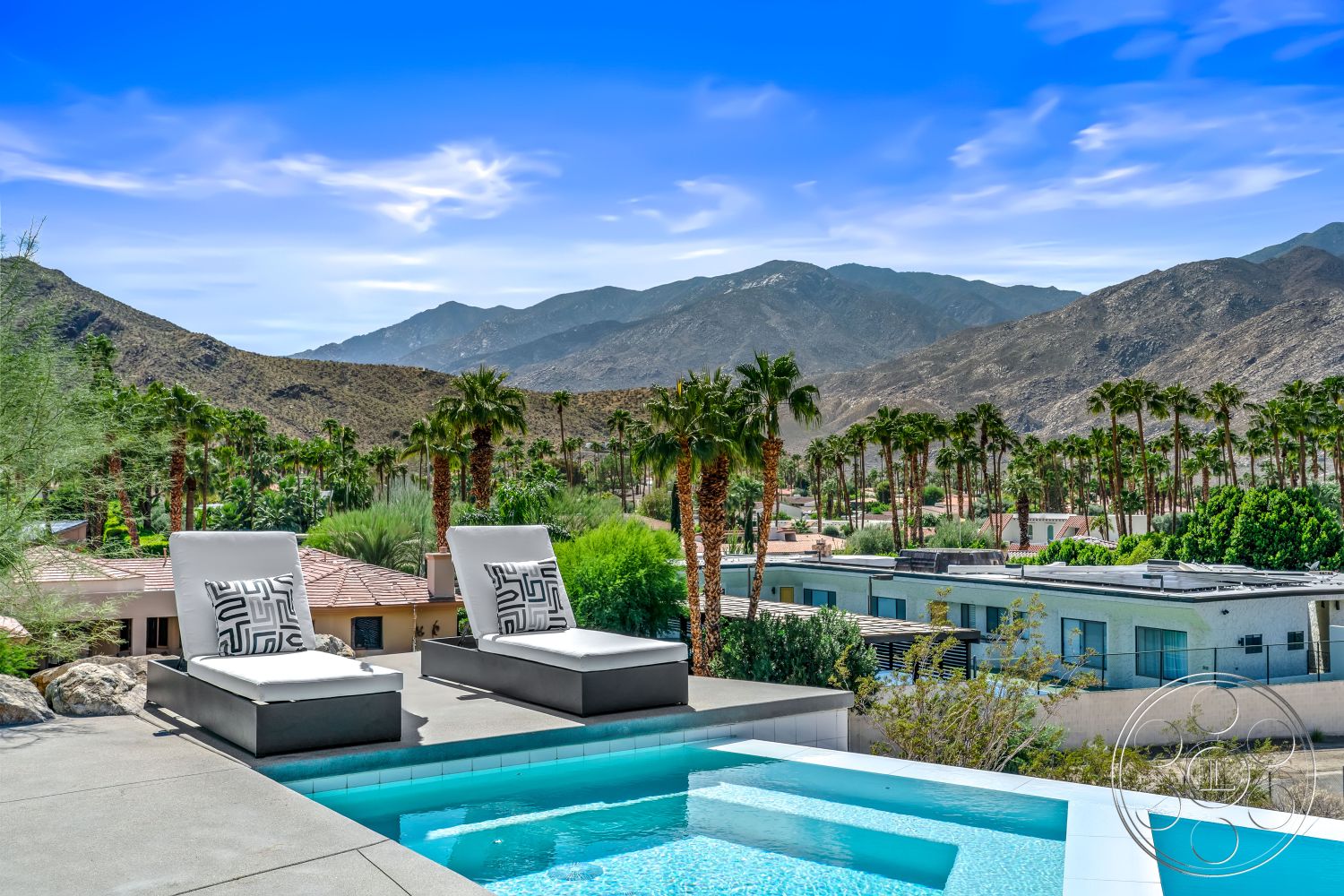Palm Springs 109 - glass railing, mountain view setting, exterior concrete pool border, concrete patio floor, rectangular infinity pool, modern outdoor lounge chairs, landscaped garden with palm trees, desert home environment, light gray concrete deck, tile pool surround, urban rooftop pool, bio-climatic architecture