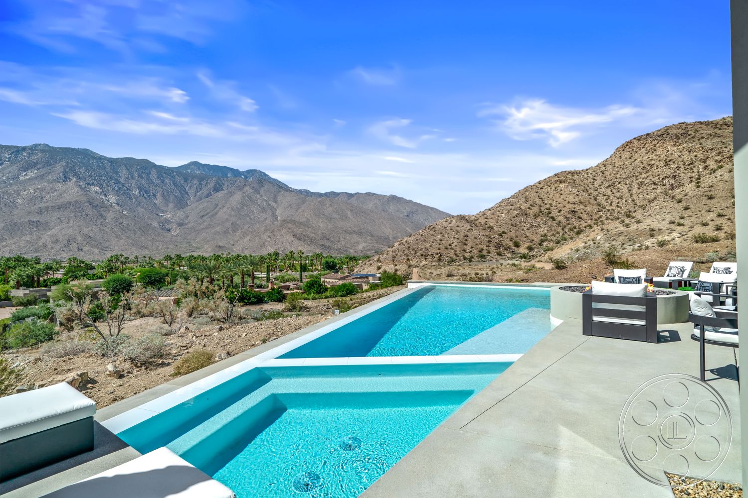 Palm Springs 109 - natural stone accents, smooth concrete flooring, landscaped backyard, landscape lighting, mountain view, desert landscape, open-air terrace, infinity pool, concrete pool deck, rectangular pool, minimalist architecture, luxury outdoor living, outdoor fire pit, modern outdoor seating area, panoramic mountain views, desert home exterior, exposed aggregate concrete patio floor, glass-railed balcony, contemporary pool design