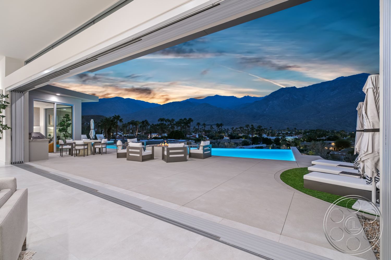 Palm Springs 109 - sunset view, textured plaster walls, mountain view setting, contemporary design aesthetics, large open layout, luxury outdoor living space, exterior concrete patio flooring, landscaped garden with palm trees, infinity pool with LED lighting, sliding glass door system, outdoor fire pit seating area, rectangular shape swimming pool, stainless steel outdoor kitchen appliances, modern lounge chairs by the pool, spacious outdoor dining area