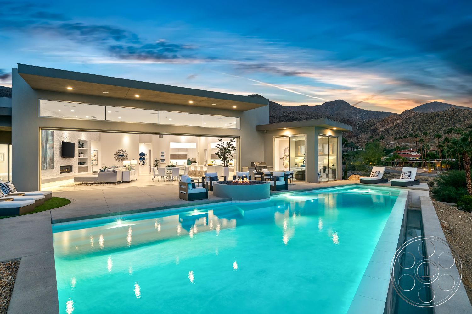 Palm Springs 109 - exterior, floor-to-ceiling windows, open-concept living space, contemporary outdoor furniture, rectangular pool, minimalist landscaping, poolside lounge area, natural stone pavers, modern Mediterranean style, concrete patio floor, modern glass sliding doors, flat roof architecture, decorative outdoor planters, exposed stone feature wall, stone fire pit area, desert mountain view, tile outdoor flooring, lush garden elements, desert sunset backdrop, wood beam ceiling accent