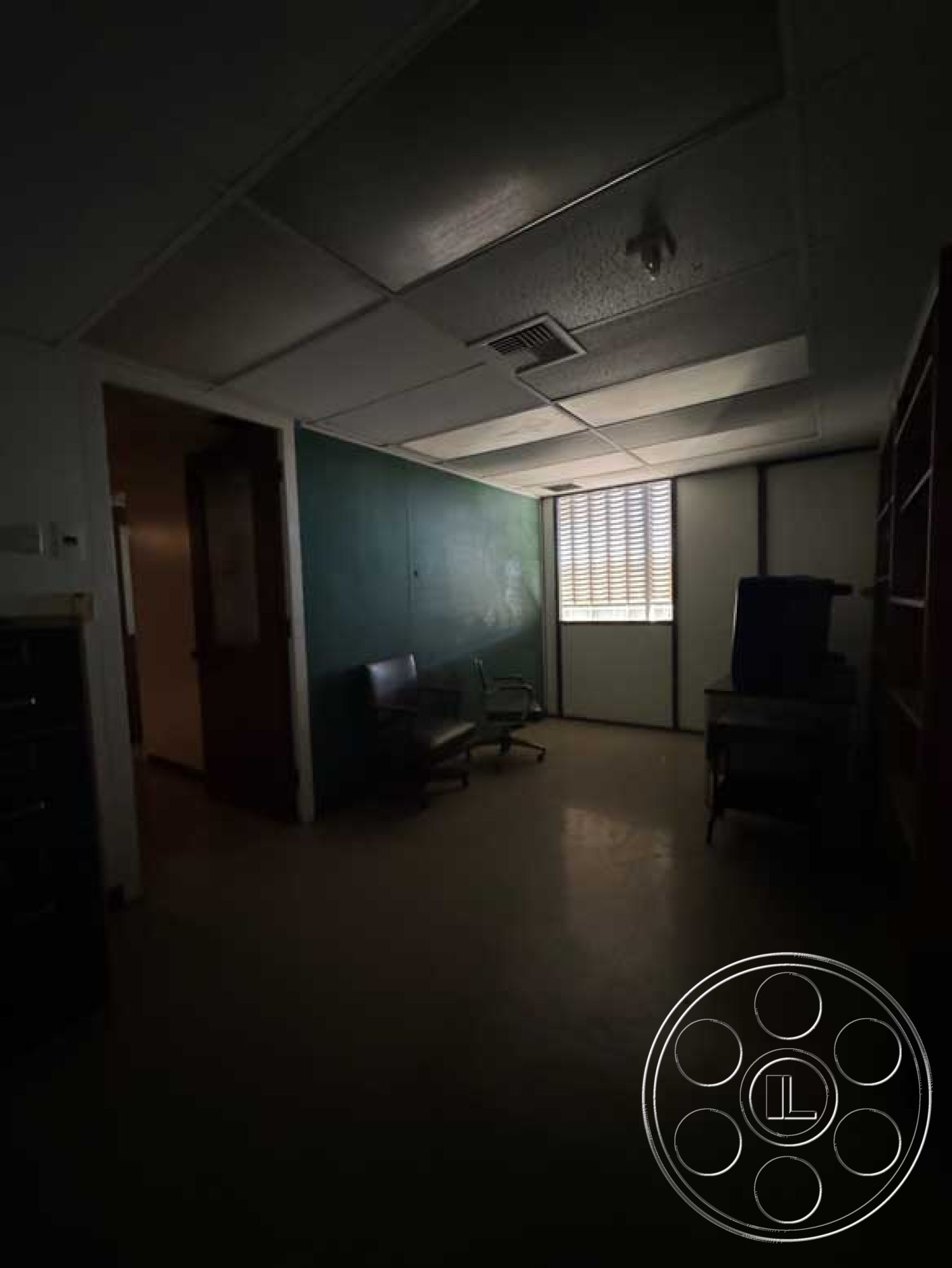 School 3 - light fixture, neutral color scheme, natural light from window, wooden door frame, interior office space, drop ceiling tiles, corner office layout, vinyl tile flooring, painted plaster walls, dual-pane window, metal office chair, multi-panel glass door, L-shaped desk