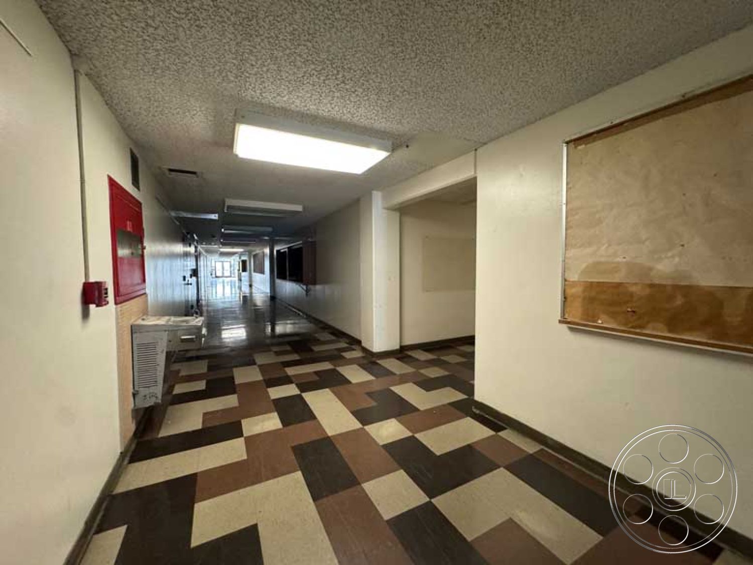 School 3 - minimalist design, interior hallway, textured plaster wall, white painted walls, exposed ceiling tiles, checkerboard tile flooring, school corridor, fluorescent ceiling lighting, fire alarm system, brown and cream vinyl tiles, administrative hallway, built-in wall compartments