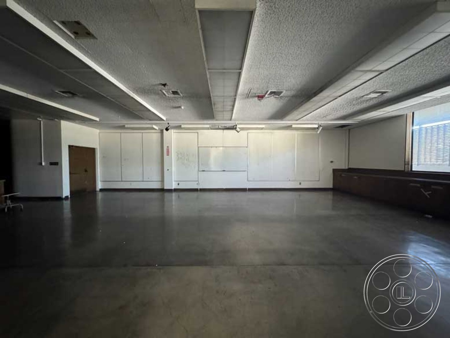 School 3 - plastered walls interior, open floor plan interior, industrial style interior, minimalist design interior, concrete flooring interior, acoustic ceiling tiles interior, large windows interior, wood paneling accent wall interior, track lighting ceiling fixture interior, built-in cabinetry interior