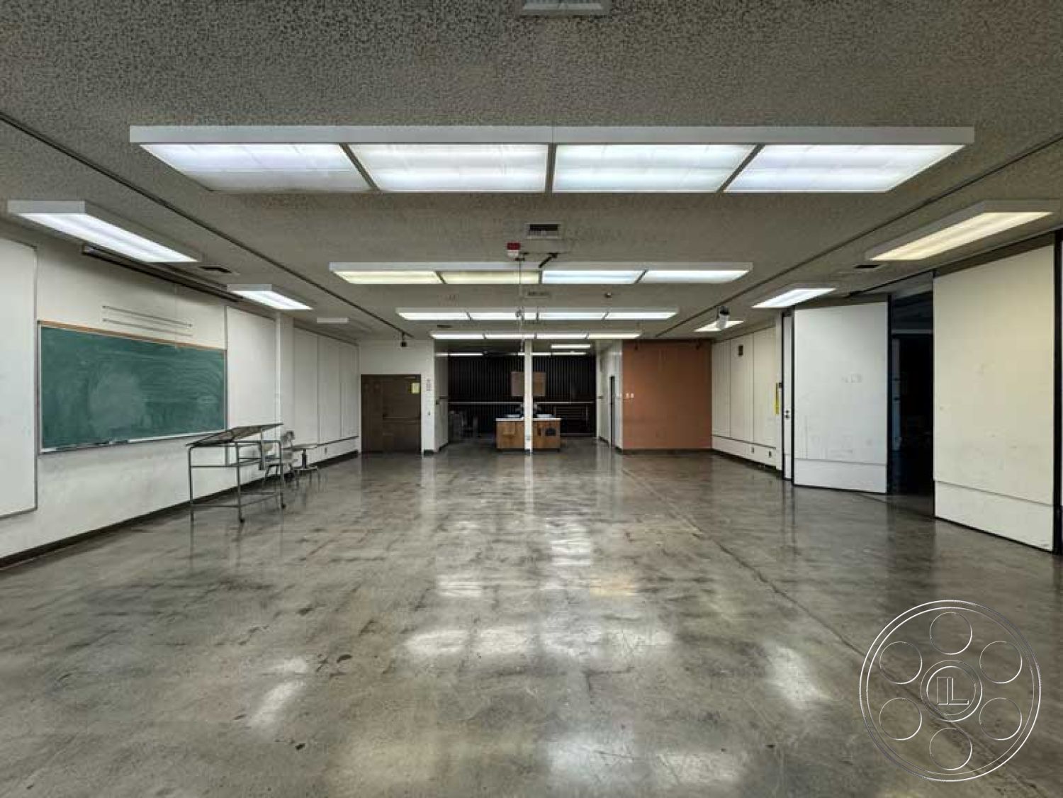 School 3 - neutral color palette, open floor plan, concrete floor, interior space, industrial lighting, chalkboard wall, plain white walls, panel door, drop ceiling with fluorescent lights, large square room, partition walls, functional classroom design, walls with minimal decoration, flexible learning environment