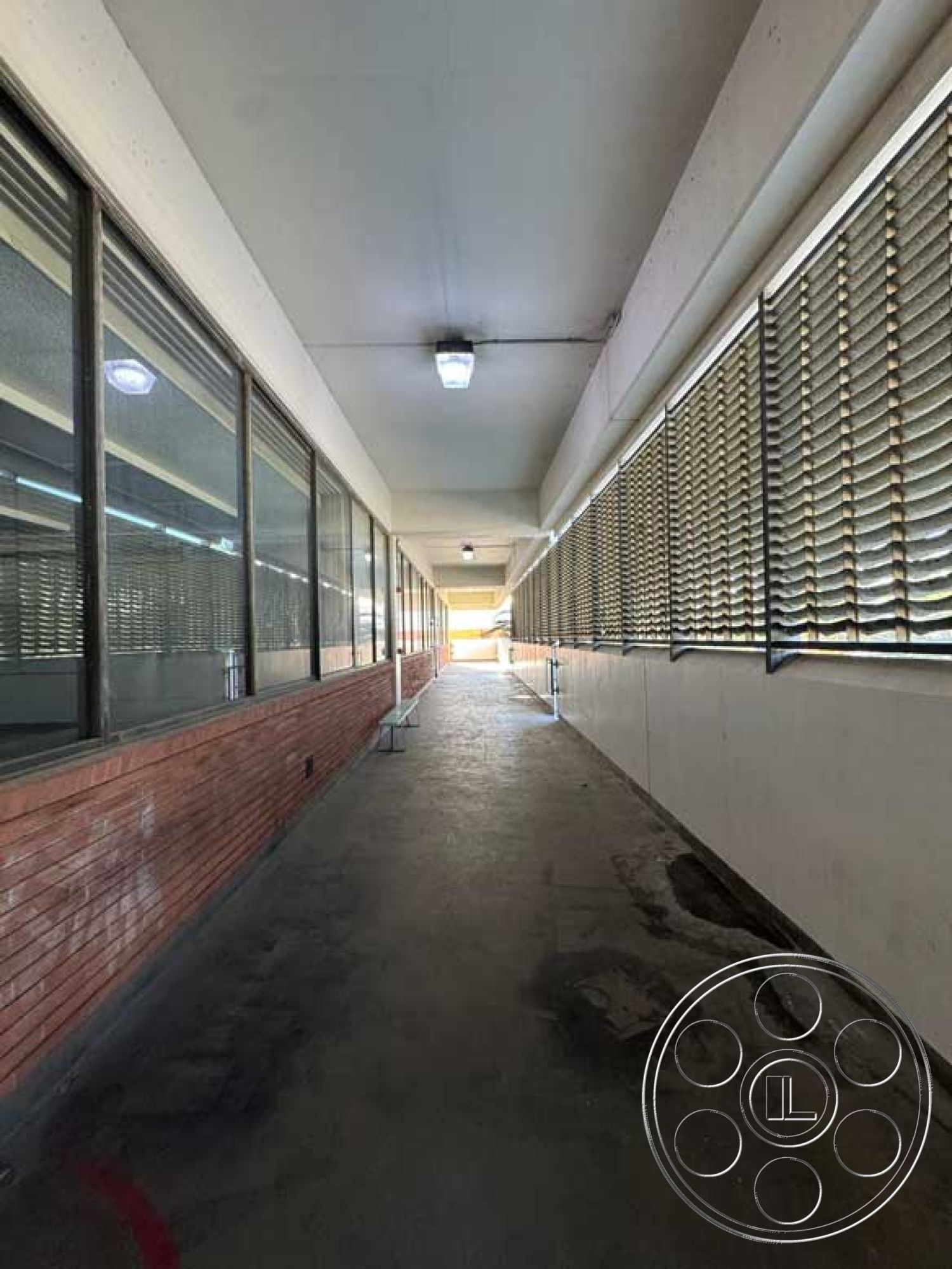 School 3 - concrete floor, fluorescent lighting, industrial style, urban setting, glass windows, exposed brick wall, commercial space, rectangular space, drop ceiling, exterior corridor, horizontal slat blinds, linear hallway