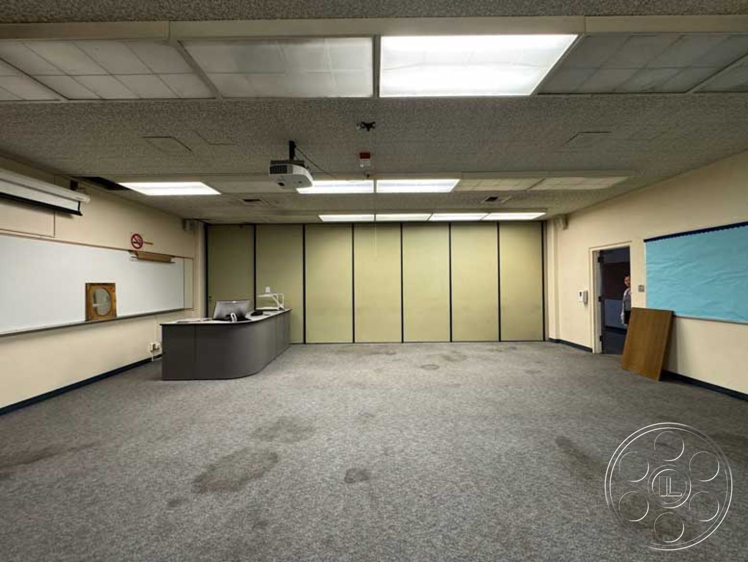 School 3 - carpet flooring, light fixtures, acoustic ceiling tiles, whiteboard wall, gray textured carpet, drywall walls, projector installation, curved reception desk, classroom setting