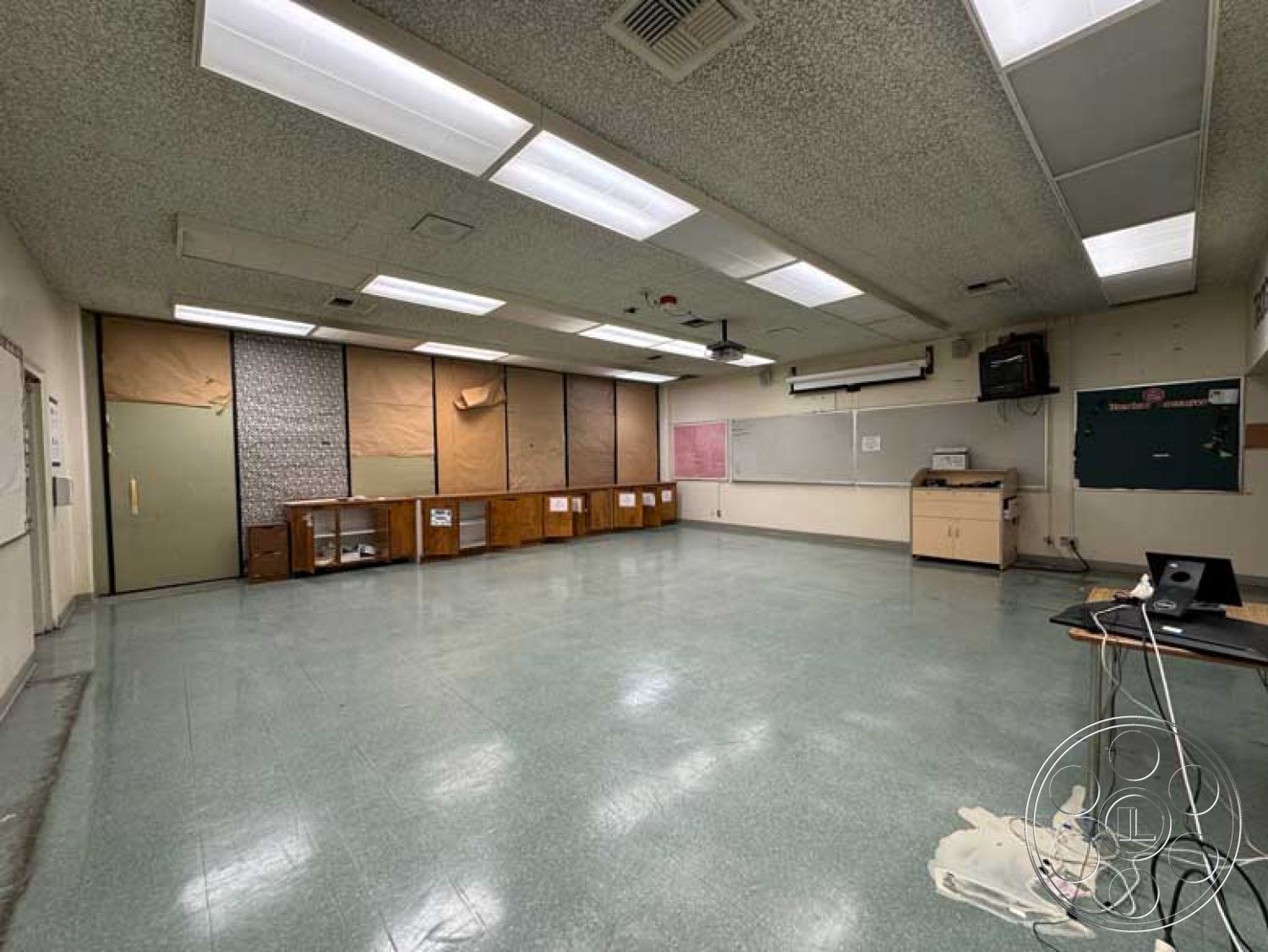 School 3 - large windows for natural light, muted color palette, textured acoustic ceiling tiles, whiteboard wall, exposed concrete block walls, built-in wooden cabinets, functional learning space, interior classroom design, black chalkboard wall, spacious classroom layout, vinyl classroom flooring, drop ceiling lights, classroom projector mount, wooden trim around windows, aerial HVAC vents