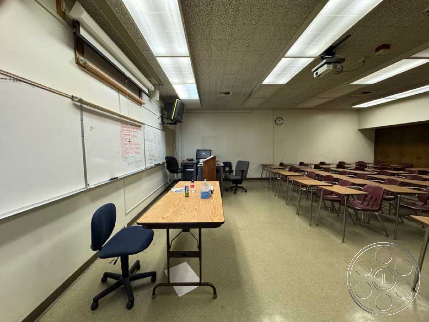 School 3 - neutral color palette, comfortable seating area, chalkboard wall, educational environment, wall-mounted projector, acoustic ceiling tiles, vinyl tile flooring, overhead projector, fluorescent ceiling lighting, interior classroom design, clock on wall, laminate desk surface, wooden podium for teaching, plastic student chairs, multi-functional classroom layout, computer workstation, organized classroom arrangement, workspace for students