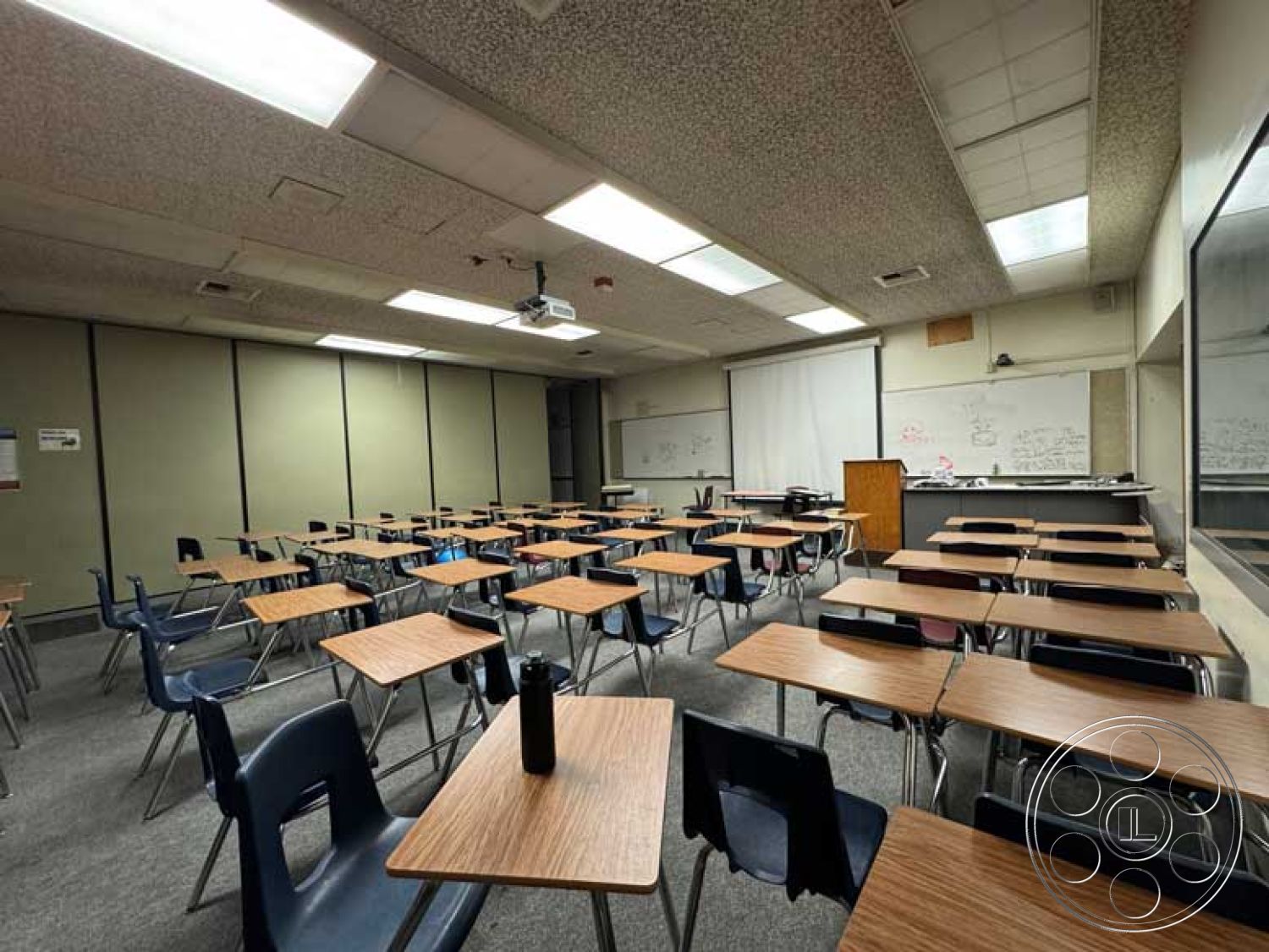 School 3 - window with blinds, built-in storage cabinets, fluorescent lighting fixtures, drop ceiling with acoustic tiles, modern educational environment, carpet classroom flooring, projection screen installation, whiteboard wall treatment, functional classroom setting, plastic student chairs, educational space interior, laminate wood classroom tables, open layout classroom design, chalkboard wall with dry erase markers, teacher's lectern, classroom with multiple seating arrangements, technology-integrated learning space