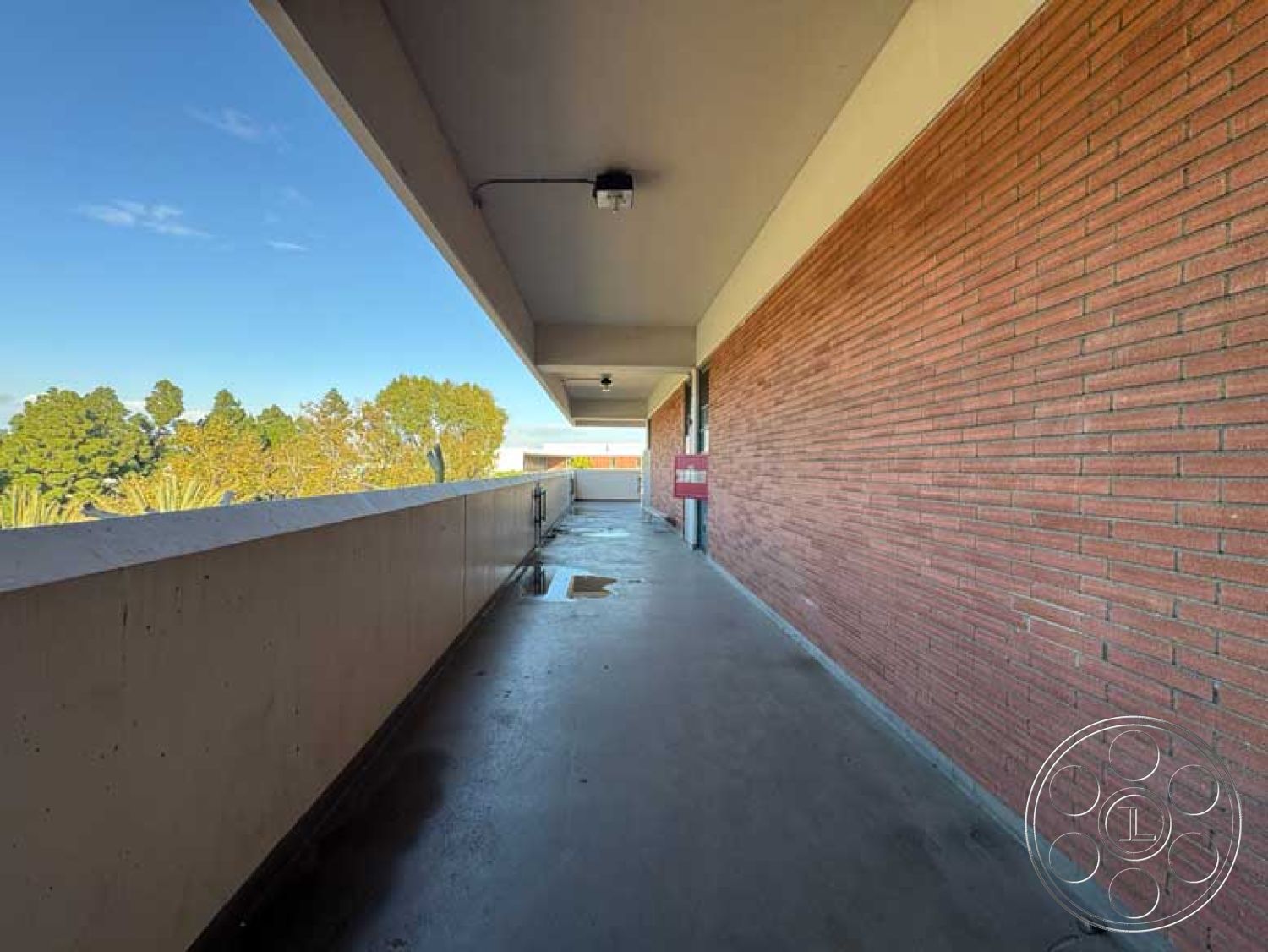 School 3 - urban setting, modern architectural style, city skyline view, flat ceiling design, exposed brick exterior walls, concrete balcony floor, rectangular balcony, overhang roof design, detailed overhead lighting fixtures, smooth concrete railing, contemporary building, dual-color facade