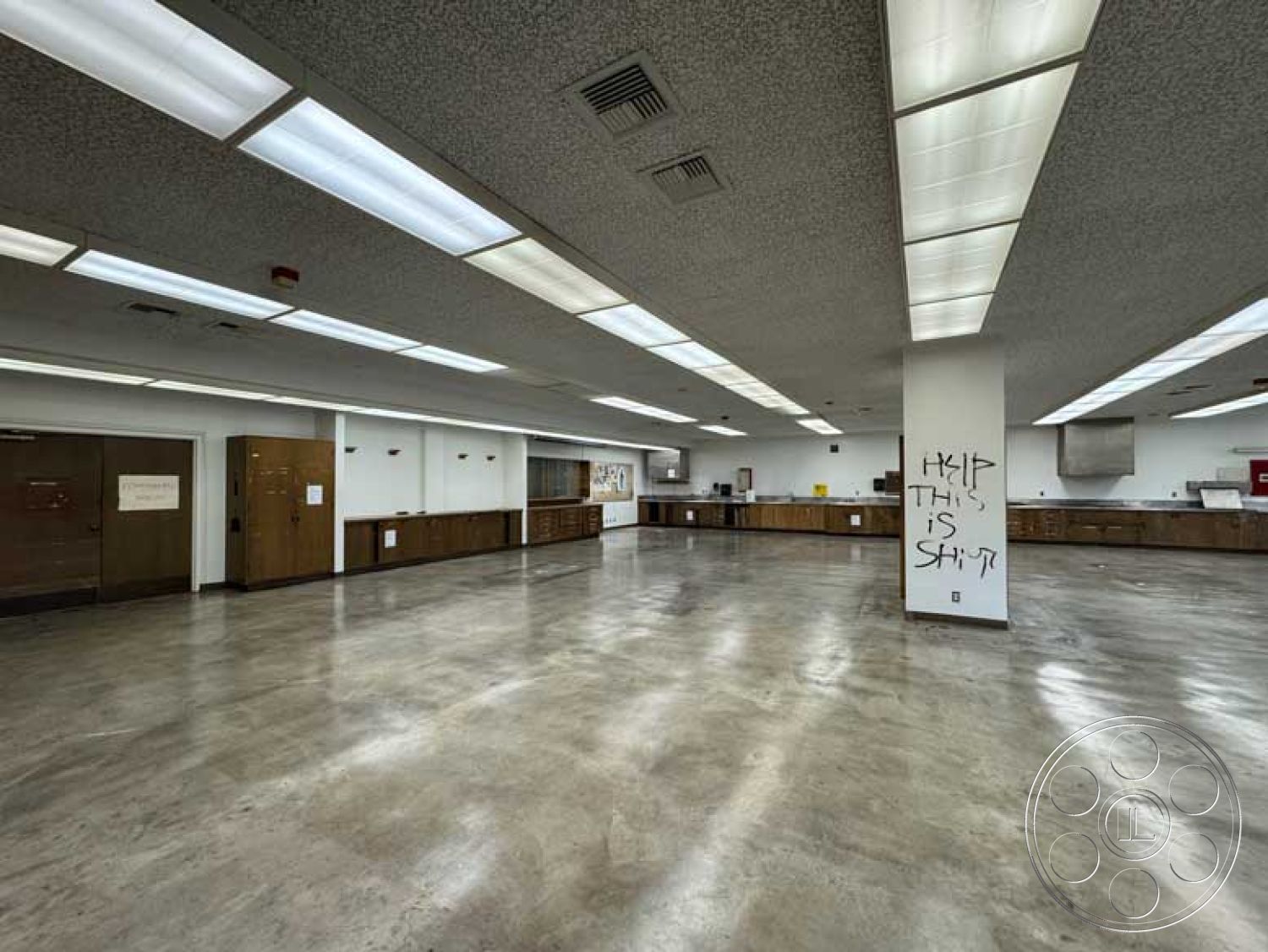 School 3 - open floor plan, polished concrete flooring, large windows for natural light, unfinished space, industrial light fixtures, white painted walls, drop ceiling with fluorescent lighting, wood cabinets with laminate finish, commercial-grade kitchen area, accessible entry doors, central air conditioning vents