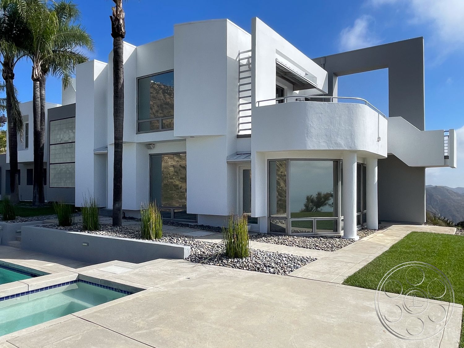 Modern 56 - exterior, landscaped garden, white stucco walls, minimalist aesthetic, open space design, rectangular swimming pool, modern architectural style, large floor-to-ceiling windows, metal staircase, flat roof design, concrete patio floor, curved balcony railing, palm trees landscaping, geometric building shapes, pebble garden border