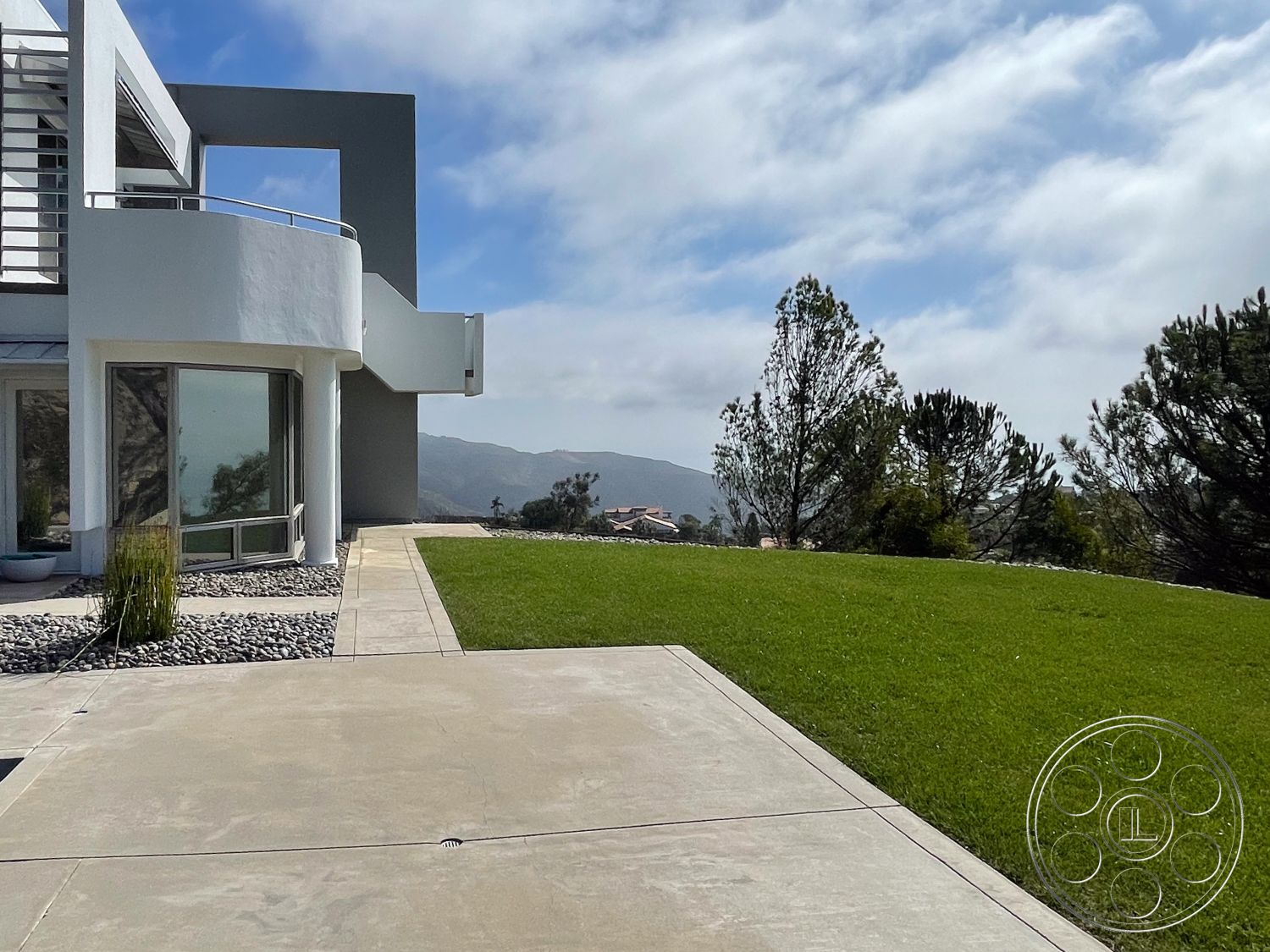 Modern 56 - exterior, low-maintenance landscaping, minimalist design elements, large glass windows, integrated outdoor space, open landscape, smooth concrete driveway, mountain view setting, natural stone border, concrete patio floor, curved building facade, decorative gravel ground cover, modern geometric architecture, landscaped lawn area, urban suburb environment