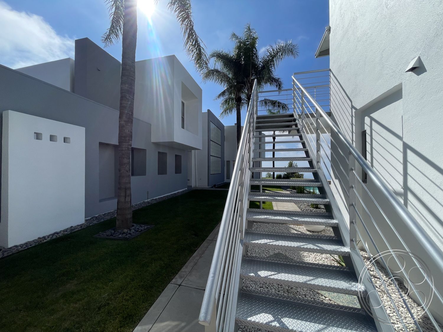 Modern 56 - exterior, modern architecture, open space layout, stucco walls, outdoor lighting fixtures, rectangular windows, metal staircase, flat roof design, landscaped garden area, aluminum railings, tropical palm landscaping, smooth white facade, polished concrete pathway