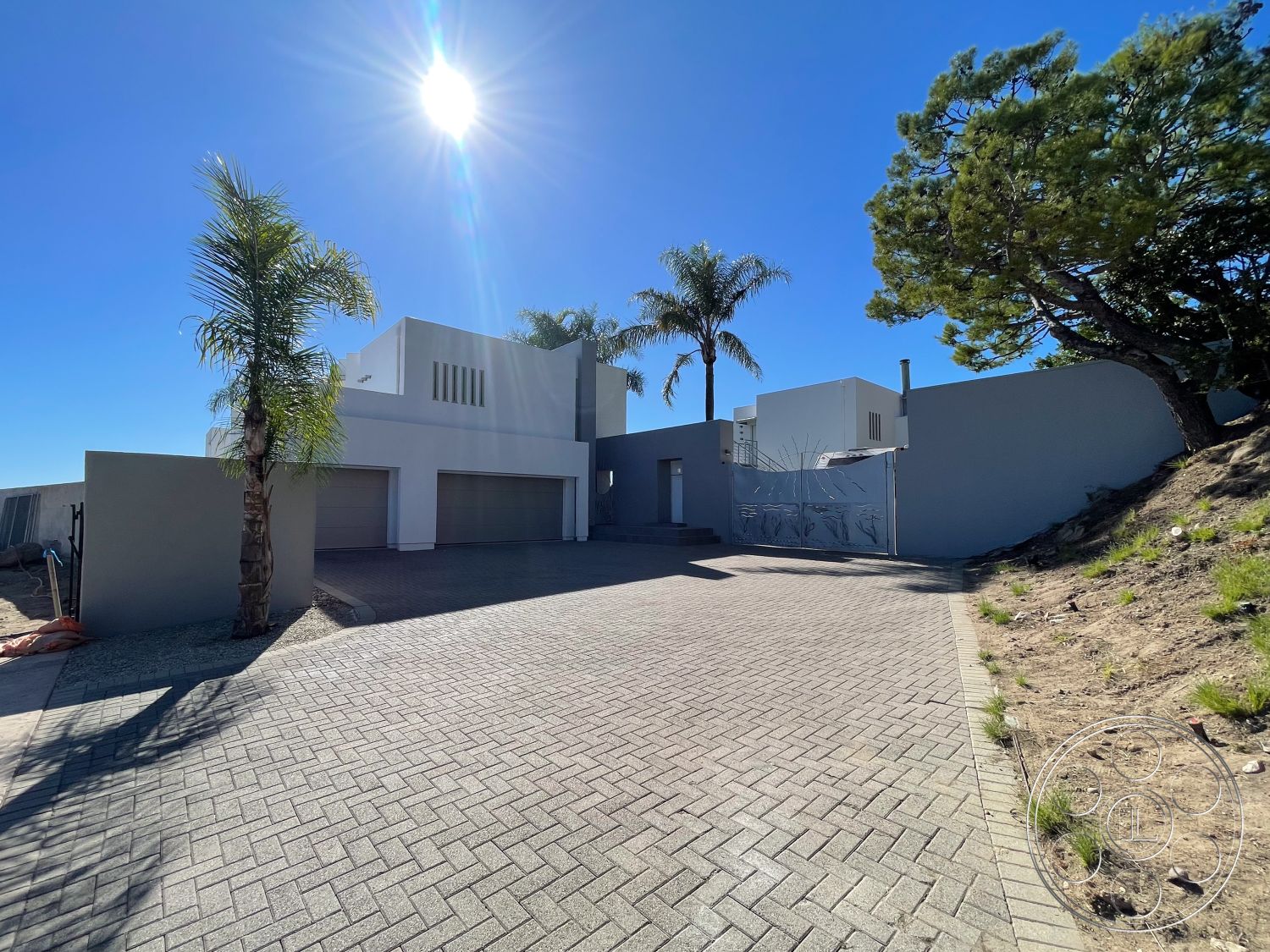 Modern 56 - white stucco walls, minimalist design elements, landscaped front yard, modern architectural style, urban residential setting, textured concrete wall, sunlit exterior, flat roof design, exterior concrete driveway, contemporary home design, elevated hillside location, paved stone driveway, horizontal window slits, palms in garden area, private garage doors