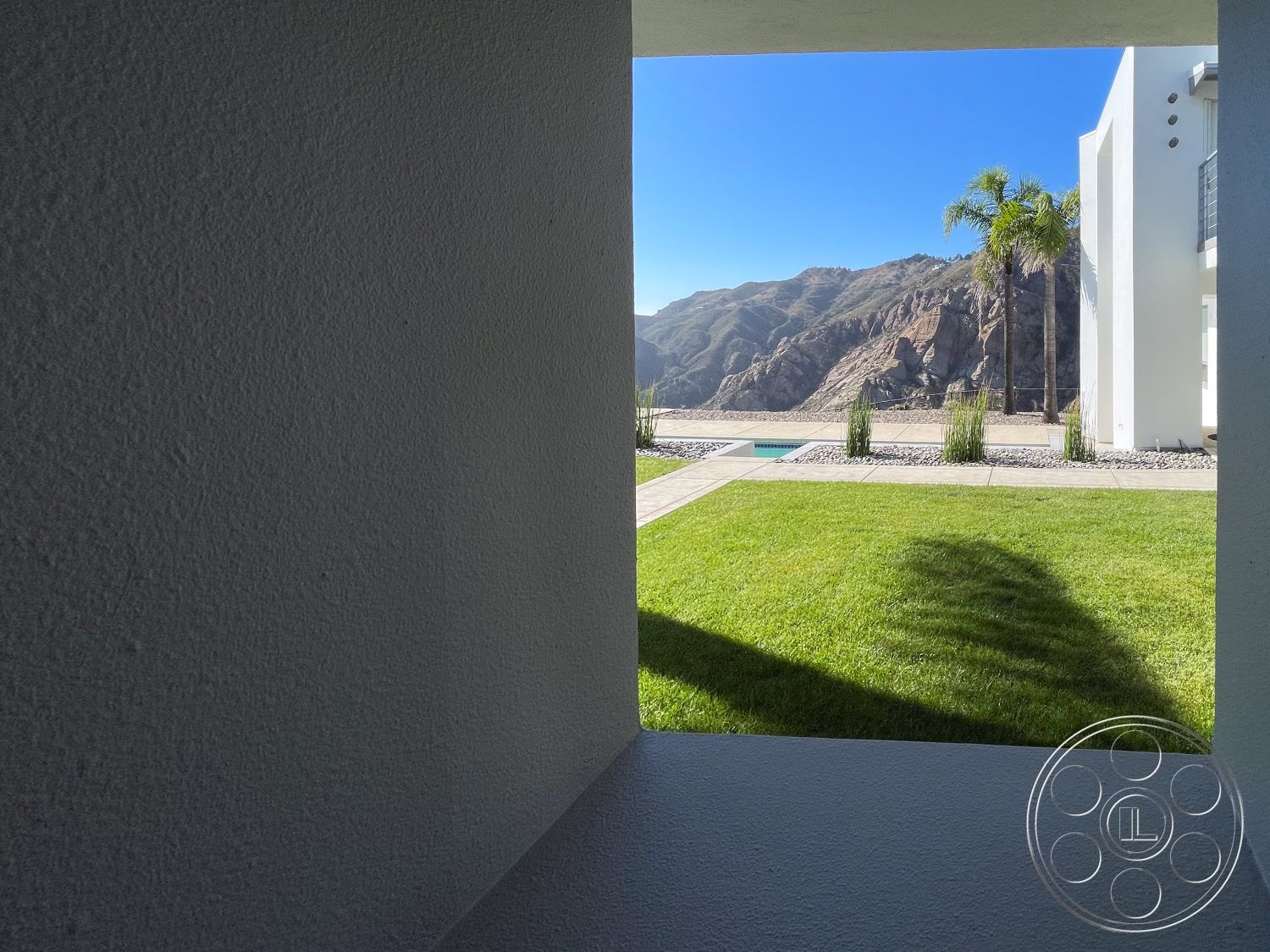 Modern 56 - exterior, white stucco walls, minimalist design, large windows for natural light, rectangular swimming pool, modern architectural style, landscape with ornamental grasses, open view of mountain landscape, lawn area with green grass, concrete patio tiles, outdoor space with mountain backdrop