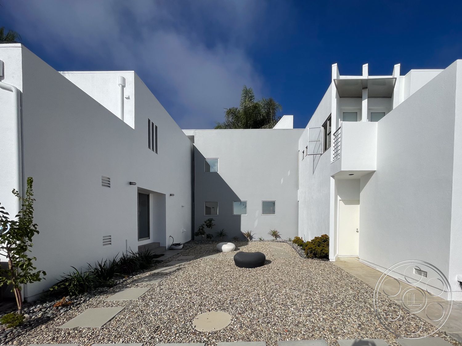Modern 56 - exterior, white stucco walls, suburban setting, geometric shapes, contemporary aesthetic, modern home, minimalist landscaping, flat roof design, pebble ground cover, palm tree landscaping, horizontal and vertical lines, ample natural light, rectangular courtyard, concrete path stones, architectural feature window openings, metal railing accents