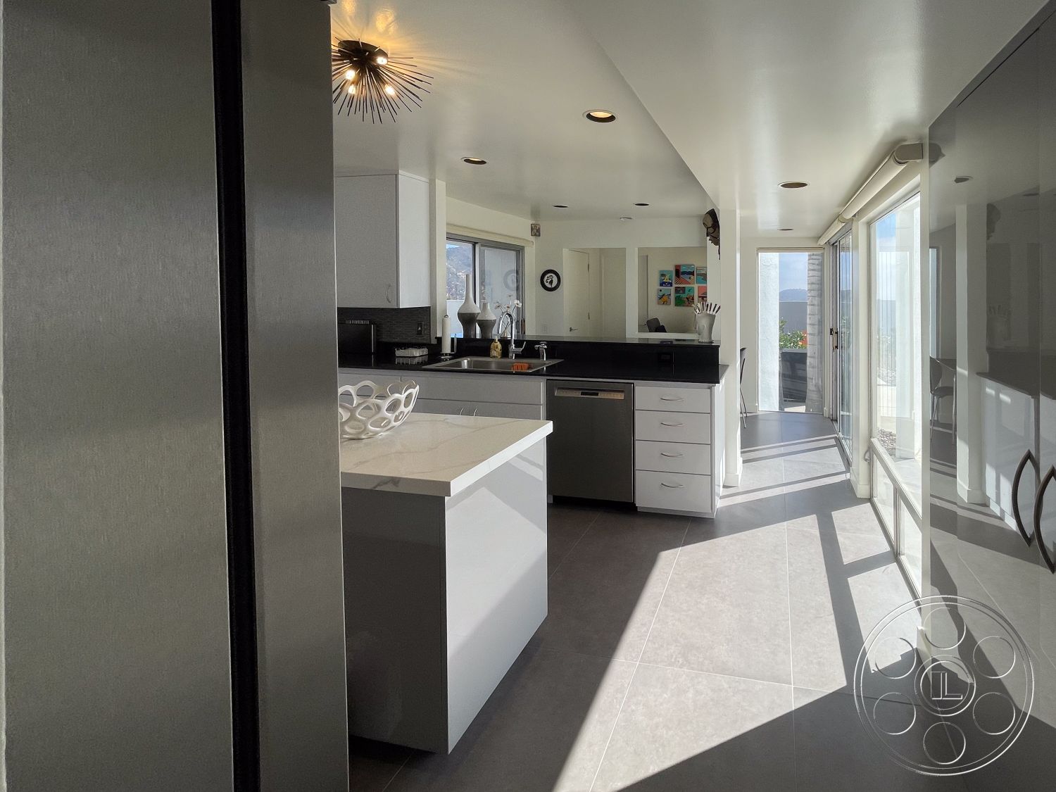 Modern 56 - glass sliding doors, contemporary dining area, smooth white walls, stainless steel kitchen appliances, modern pendant light fixture, interior kitchen space, natural light through large windows, minimalist kitchen decor, open layout design, gray porcelain tile flooring, white cabinetry with modern hardware, black quartz countertop on kitchen island, counter-height seating area, integrated kitchen sink, urban setting with skyline view