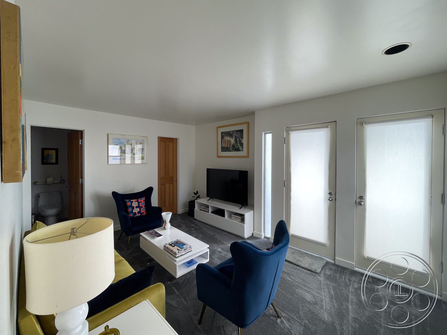 Modern 56 - minimalist decor, beige sofa, contemporary furniture, open layout, wall-mounted television, artwork on walls, large glass doors, blue accent chairs, soothing color palette, textured plaster walls, modern entertainment unit, round side table, gray carpet flooring, flush ceiling lights, interior living room, white painted walls, crown molding details, wood door frames, natural light flow