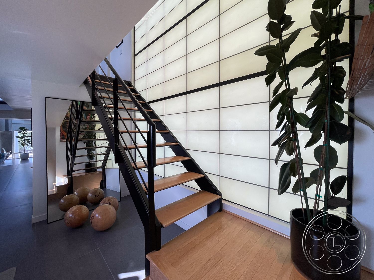 Modern 56 - ceramic tile flooring, indoor greenery, textured wall treatment, brightly lit space, modern decorative planters, contemporary architectural design, glass wall panels, black metal stair railings, minimalist entryway, open concept floor plan, large mirror accent, exposed wooden staircase, glowing backlit wall, natural hardwood stair treads