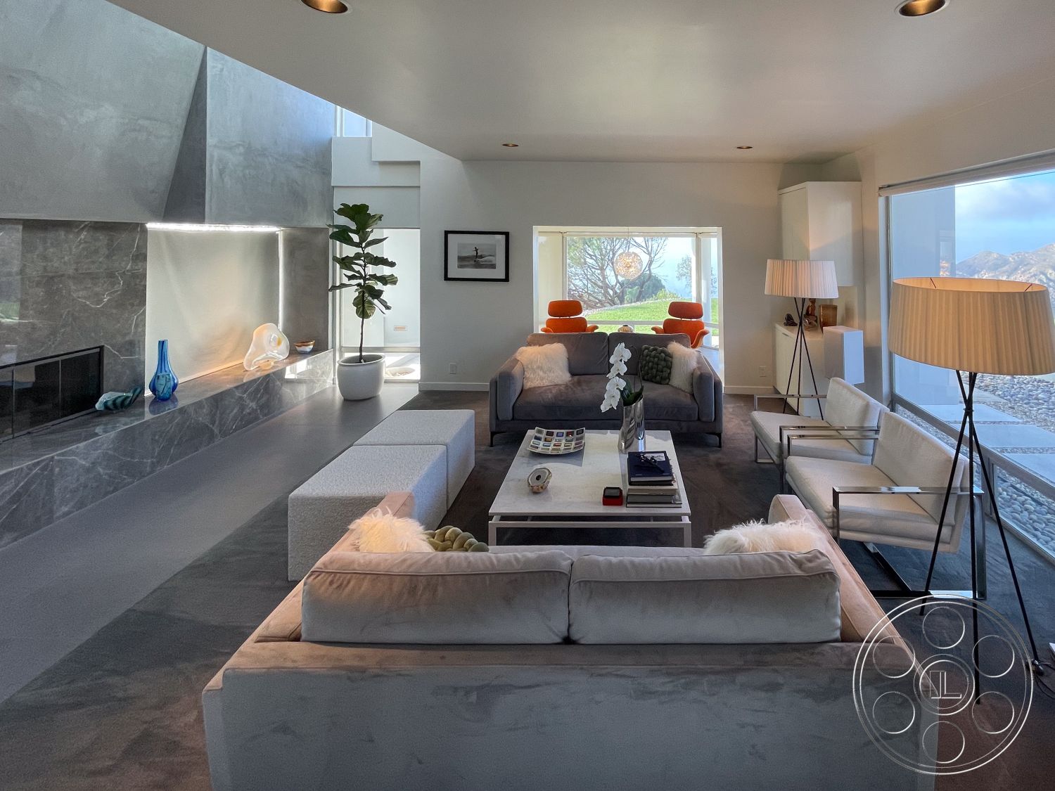 Modern 56 - open space layout, floor-to-ceiling windows, wooden side table, marble accent wall, dark flooring, rectangular coffee table, textured fabric cushions, interior living room, minimalist decor style, white painted walls, green indoor plant accent, contemporary floor lamps, view of hillside landscape, concrete fireplace surround, soft grey sectional sofa, white modern armchairs, artistic glass decor