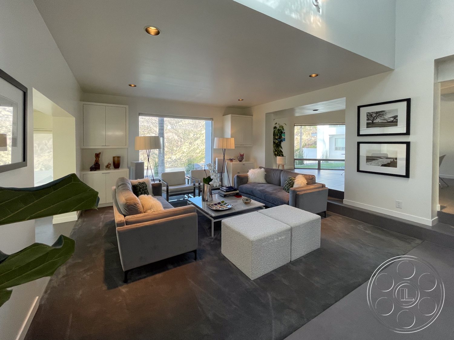 Modern 56 - hardwood flooring, open floor plan, floor-to-ceiling windows, white cabinetry, vaulted ceiling, textured plaster walls, soft lighting fixtures, minimalist coffee table, comfortable seating area, neutral color scheme, interior living room, contemporary furniture design, natural light emphasis, modern table decor, light gray sofa upholstery, indoor plants accent, artwork framed gallery wall, direct outdoor access