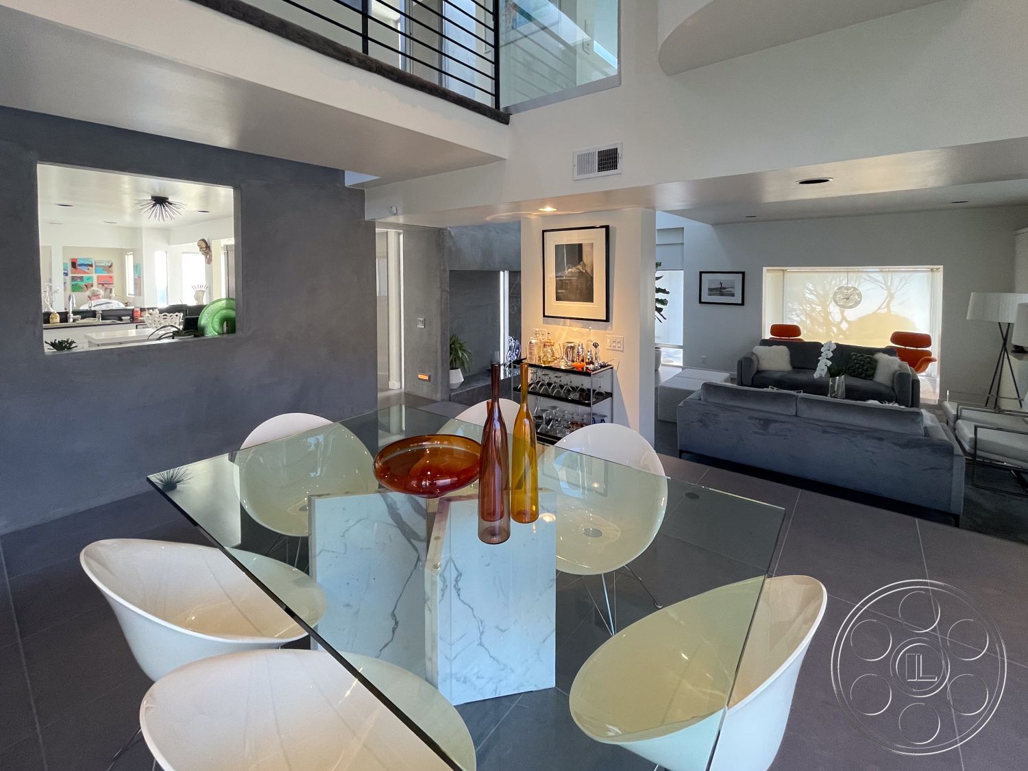 Modern 56 - minimalist decor, neutral color palette, open concept living space, stylish accent pillows, natural light through large windows, metal stair railings, exposed ceiling with recessed lighting, contemporary living room design, dark tile flooring, glass dining table with marble base, white curved dining chairs, grey textured plaster walls, modern decorative art, sunny, inviting atmosphere