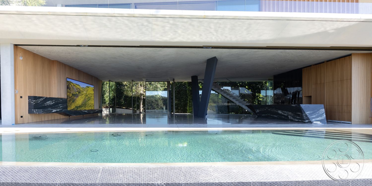 Modern 516 - rectangular swimming pool, modern architectural style, outdoor living area, monochromatic color palette, landscaped garden setting, interior floor-to-ceiling windows, interior open floor plan, interior polished concrete flooring, exterior glass sliding doors, exterior infinity pool, exposed structural steel beams, textured concrete ceiling, interior wood accent walls, exterior concrete patio, sliding glass partition wall, natural light-focused design