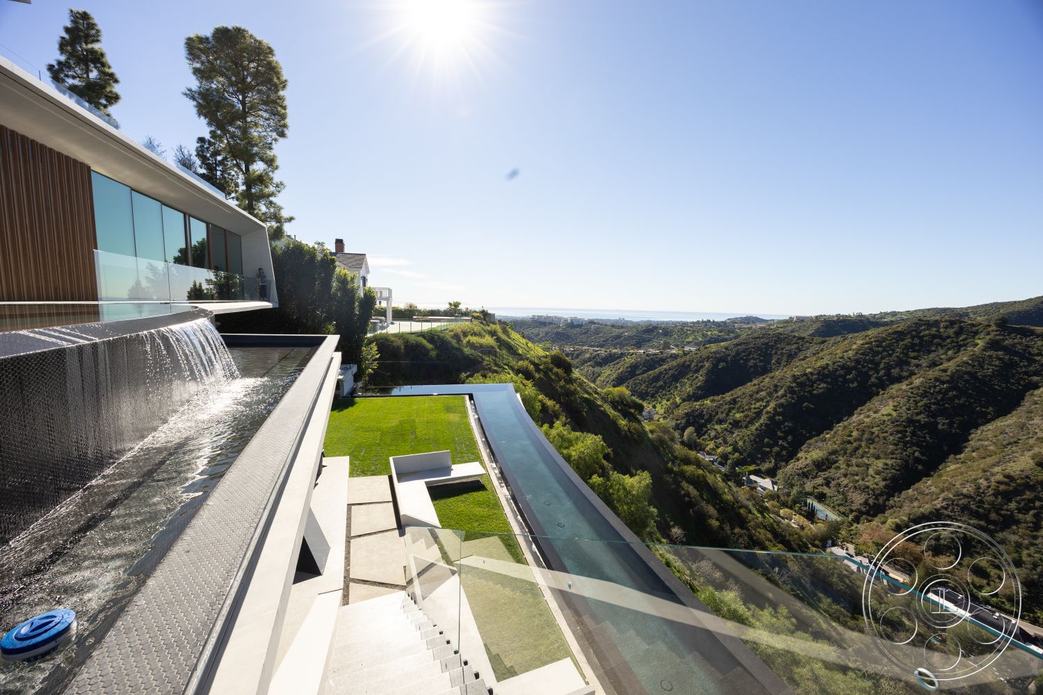 Modern 516 - exterior, glass railing, water feature, concrete steps, sliding glass door, modern architectural style, landscaped lawn, infinity pool, rectangular pool, outdoor living area, stone patio flooring, concrete pool border, stainless steel pool edge, natural hillside setting, wood paneling details, expansive mountain view, sloped lot design, urban luxury home