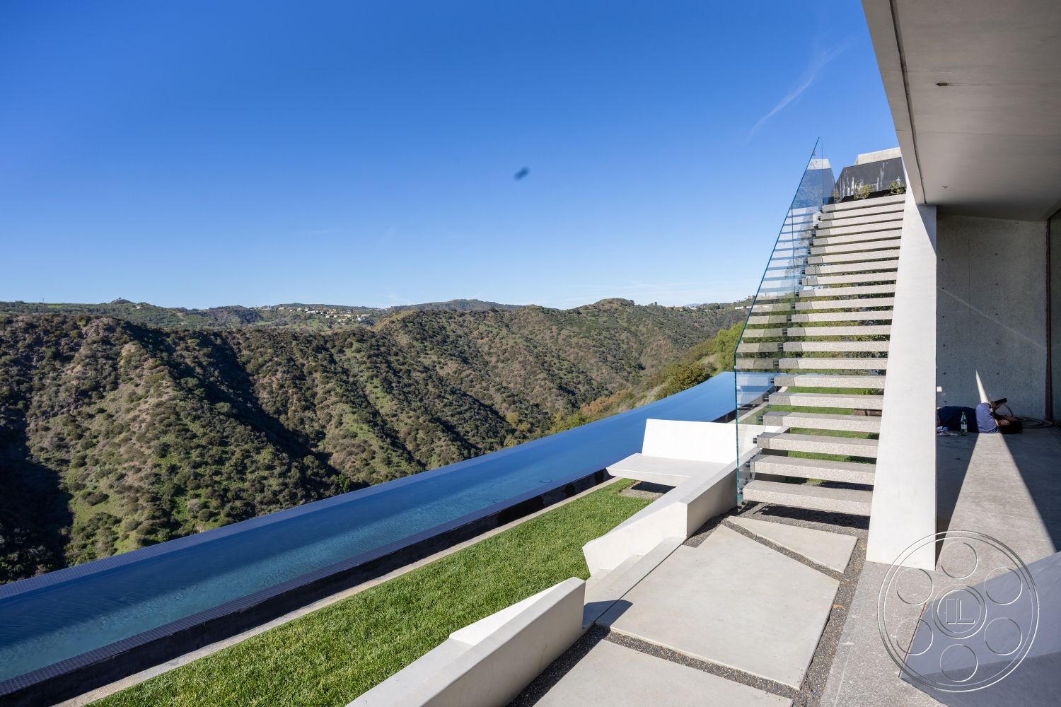 Modern 516 - clean lines, minimalist design, glass railings, concrete steps, grass lawn, outdoor living space, modern architectural style, landscape integration, stone landscaping, mountain view setting, concrete patio floor, contemporary home exterior, infinity pool edge, elevated pool terrace, exterior glass staircase