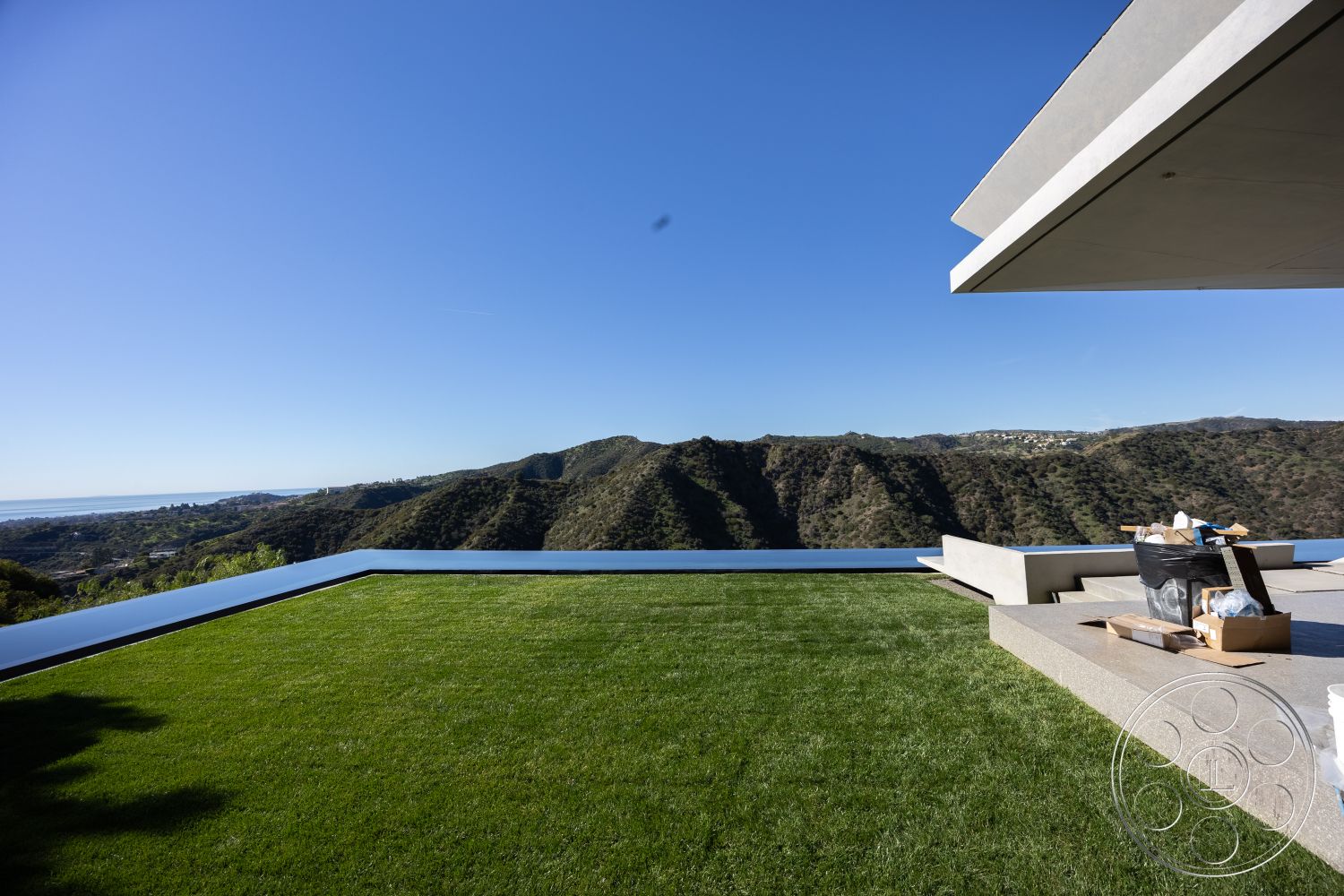 Modern 516 - interior: concrete patio floor, interior: cantilevered concrete overhang, interior: glass railing, exterior: infinity edge pool, exterior: expansive grass lawn, exterior: mountain view backdrop, exterior: modern architectural style, interior: minimalistic design, exterior: open-air terrace, exterior: polished stone surround, exterior: hillside location, interior: large sliding glass doors