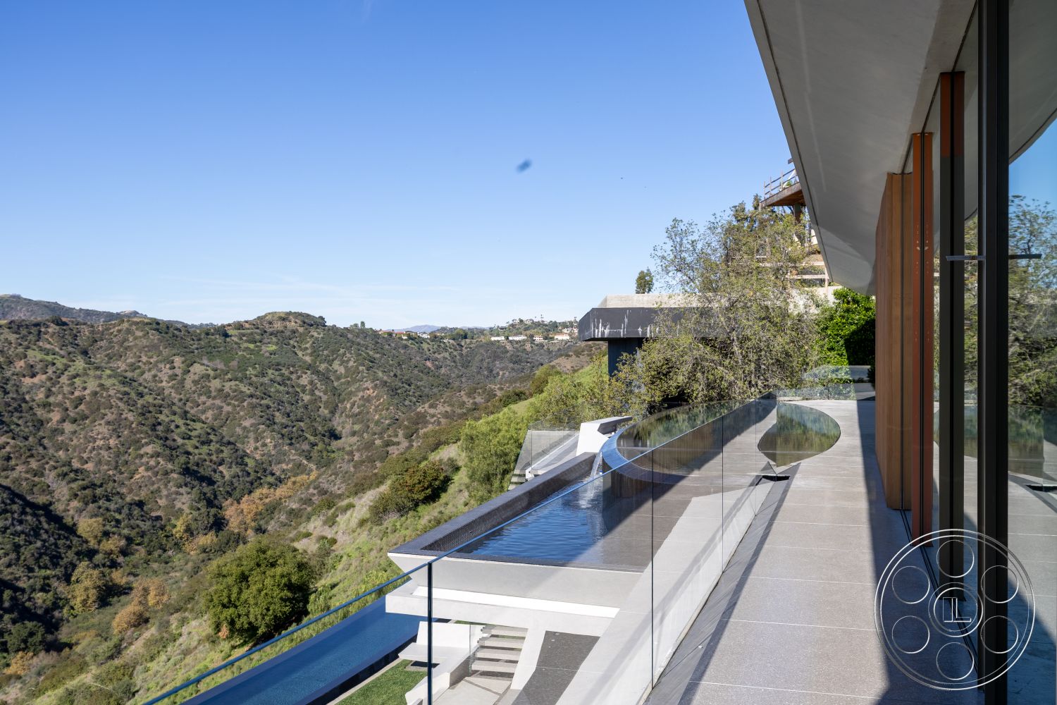 Modern 516 - natural stone accents, minimalist aesthetic, open floor plan, landscape view, floor-to-ceiling windows, stone pathway, modern architectural style, elevated terrace, hillside location, outdoor entertaining area, curved pool design, sloping hillside, concrete patio floor, smooth plaster wall finishes, glass balcony railings, infinity pool edge, exterior hardwood cladding, desert greenery, dramatic lines in architecture