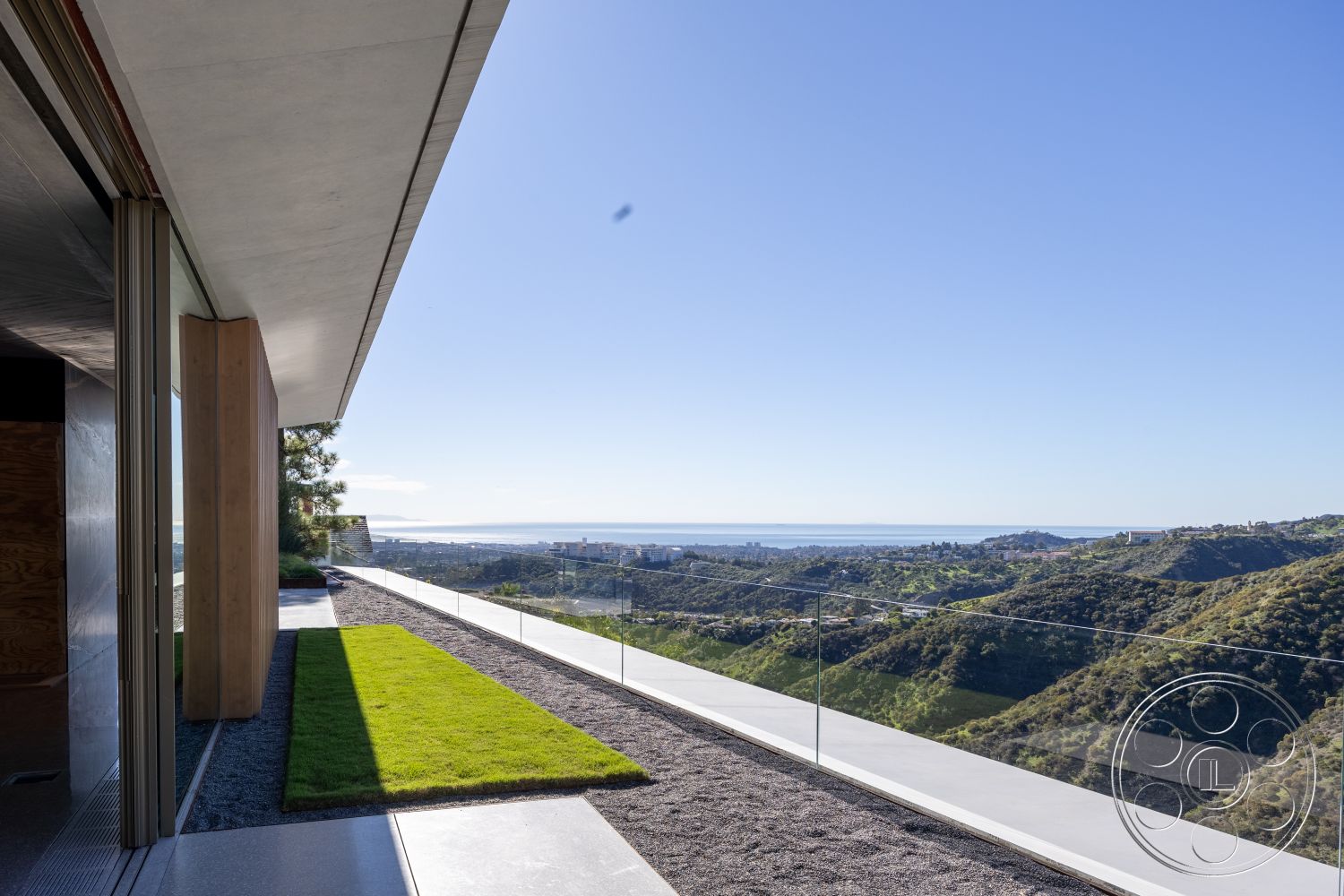 Modern 516 - open floor plan, floor-to-ceiling windows, gravel pathway, modern architectural style, sunlit terrace, mountain view setting, contemporary outdoor living space, exterior glass railing, scenic hillside location, horizontal lines in architecture, concrete overhang, wood accent columns, minimalist landscaping with grass