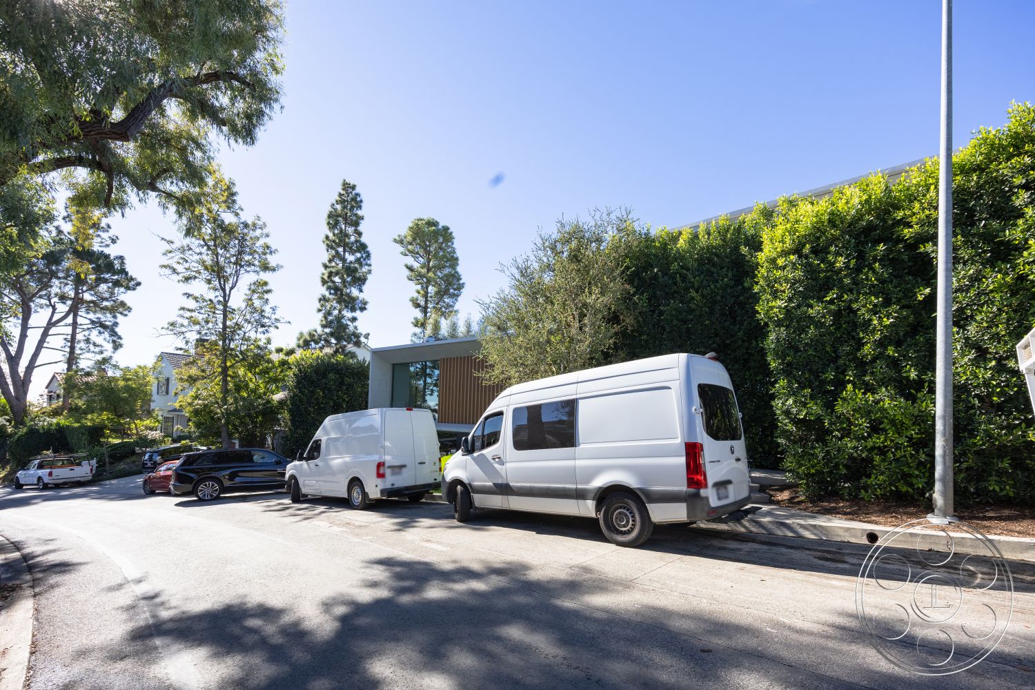 Modern 516 - surrounding greenery, contemporary home design, asphalt road surface, exterior landscaping with trees, curved road design, modern architecture with large windows, urban setting with residential buildings, parking area with multiple vehicles, nearby shrubbery and hedges, suburban neighborhood environment