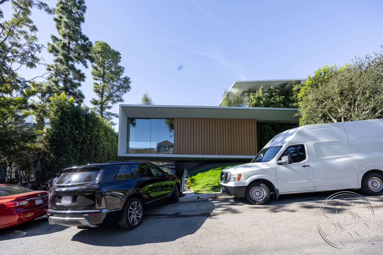 Modern 516 - exterior, modern architecture, minimalist design, open floor plan, city view, surrounding trees, urban setting, sustainable materials, concrete driveway, large floor-to-ceiling windows, geometric forms, flat roof design, stucco exterior walls, natural light emphasis, vertical wood slat accents, sloped front yard landscaping, driveway with paving stones, integrated garage