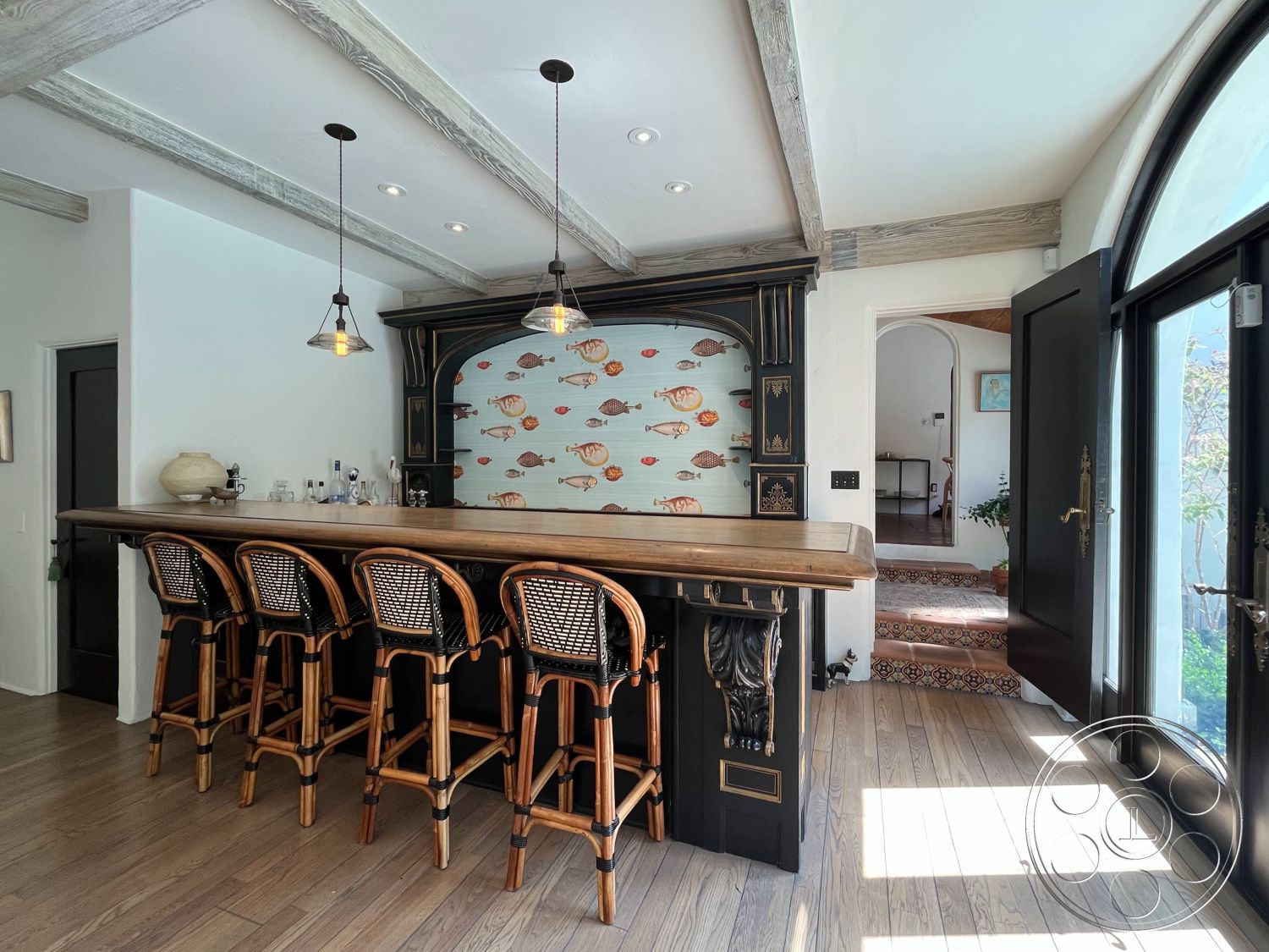 Medit 166 - hardwood flooring, open floor plan, shiplap walls, natural light from large windows, arched doorways, wooden bar counter, wood beam ceiling, interior bar area, custom black cabinetry, bamboo bar stools, fish-themed wallpaper, light pendant fixtures, ornate tile flooring, entryway with detailed tiles, tranquil coastal decor, inviting home atmosphere