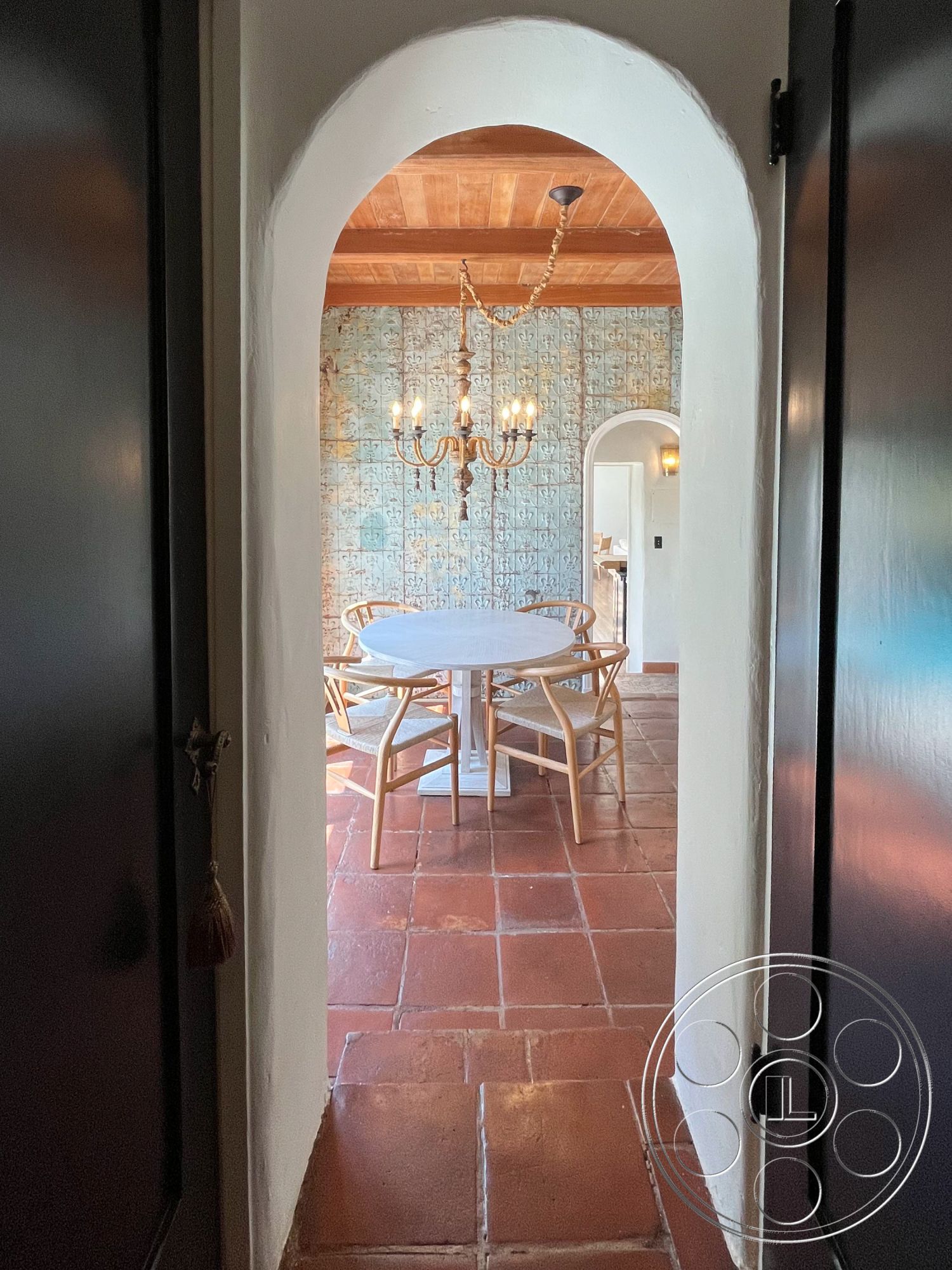 Medit 166 - decorative wall tiles, ceramic tile flooring, round dining table, soft natural light, intimate gathering space, Mediterranean style, textured plaster walls, arched doorway, open dining area, historic architectural details, woven dining chairs, traditional chandelier, crafted wooden ceiling, rustic floor tiles, warm earthy tones, stylized wall decor, cozy dining ambiance