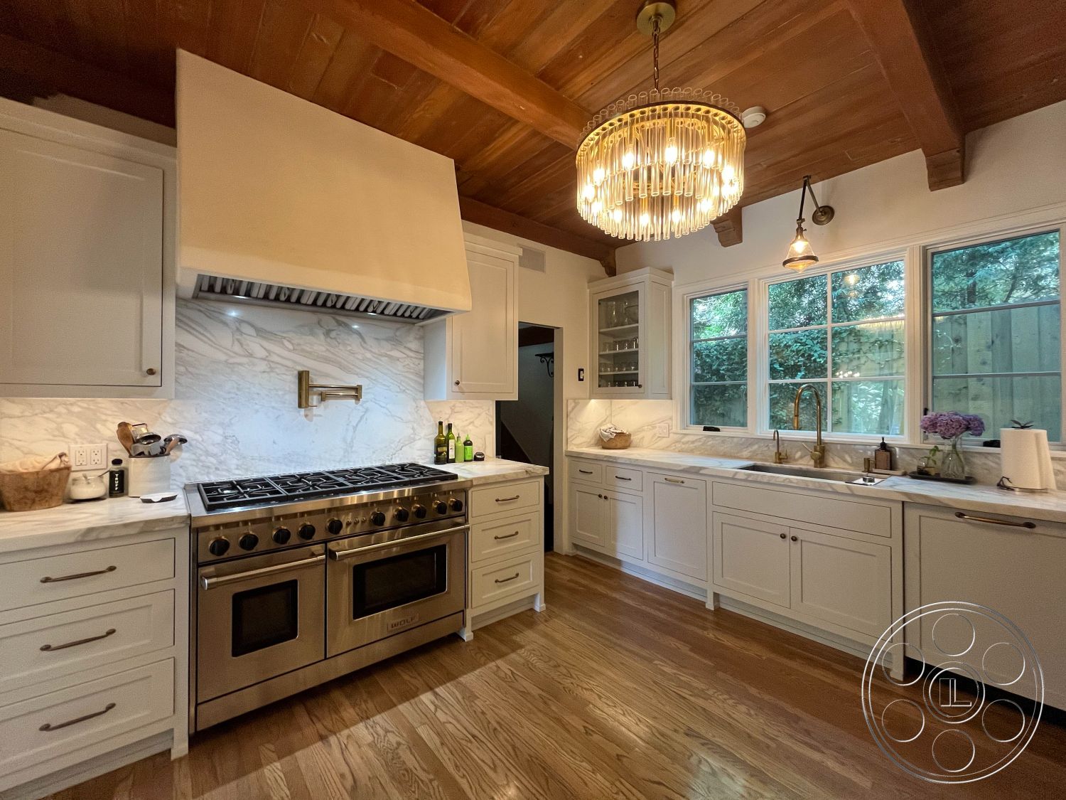 Medit 166 - modern pendant lighting, floor-to-ceiling windows, marble countertop, exposed wood ceiling beams, open kitchen layout, natural light-filled space, stainless steel gas range, marble kitchen backsplash, hardwood kitchen floors, suburban backyard view, kitchen island with seating, white shaker-style cabinets, brushed nickel cabinet hardware, wooden kitchen table