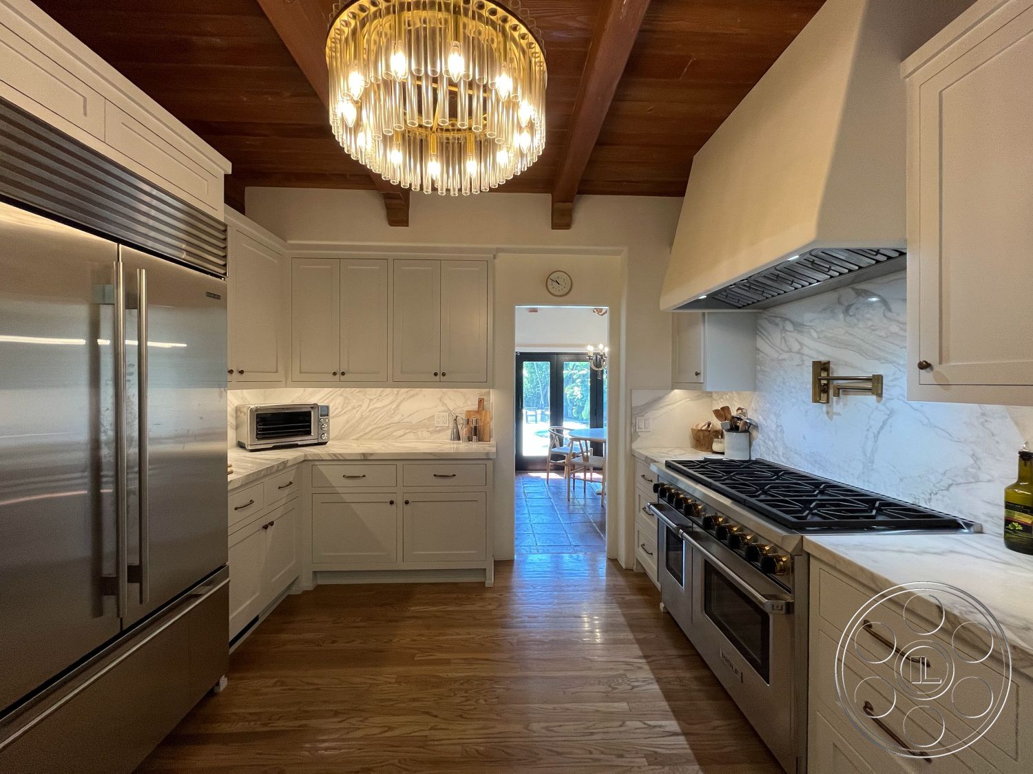 Medit 166 - neutral color palette, hardwood flooring, large windows for natural light, modern appliances, stainless steel refrigerator, marble kitchen countertops, recessed lighting fixtures, interior kitchen, exposed wooden ceiling beams, open floor plan kitchen, modern chandelier lighting, spacious cooking area, tile kitchen backsplash, kitchen island with seating, white shaker-style cabinets, brass kitchen faucet, gas range with hood, pantry storage cabinets, view of outdoor dining area, luxury chef's kitchen