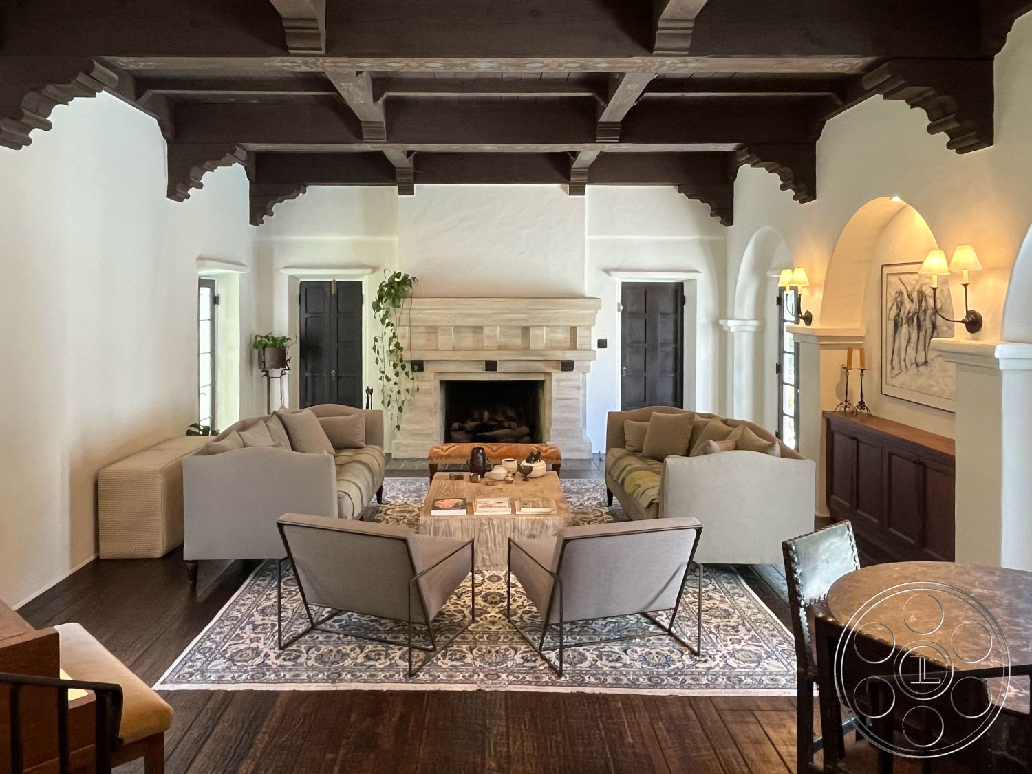 Medit 166 - hardwood flooring, cozy atmosphere, decorative wall art, arched doorways, textured plaster walls, stone coffee table, Mediterranean architectural style, elegant area rug, exposed wood ceiling beams, interior living room, stone fireplace surround, custom built-in cabinetry, vaulted living room ceiling, indoor plant accents, large windows with views, individual sitting areas, neutral-colored sofas, dimensional wall sconces, warm natural lighting, wood-framed doors