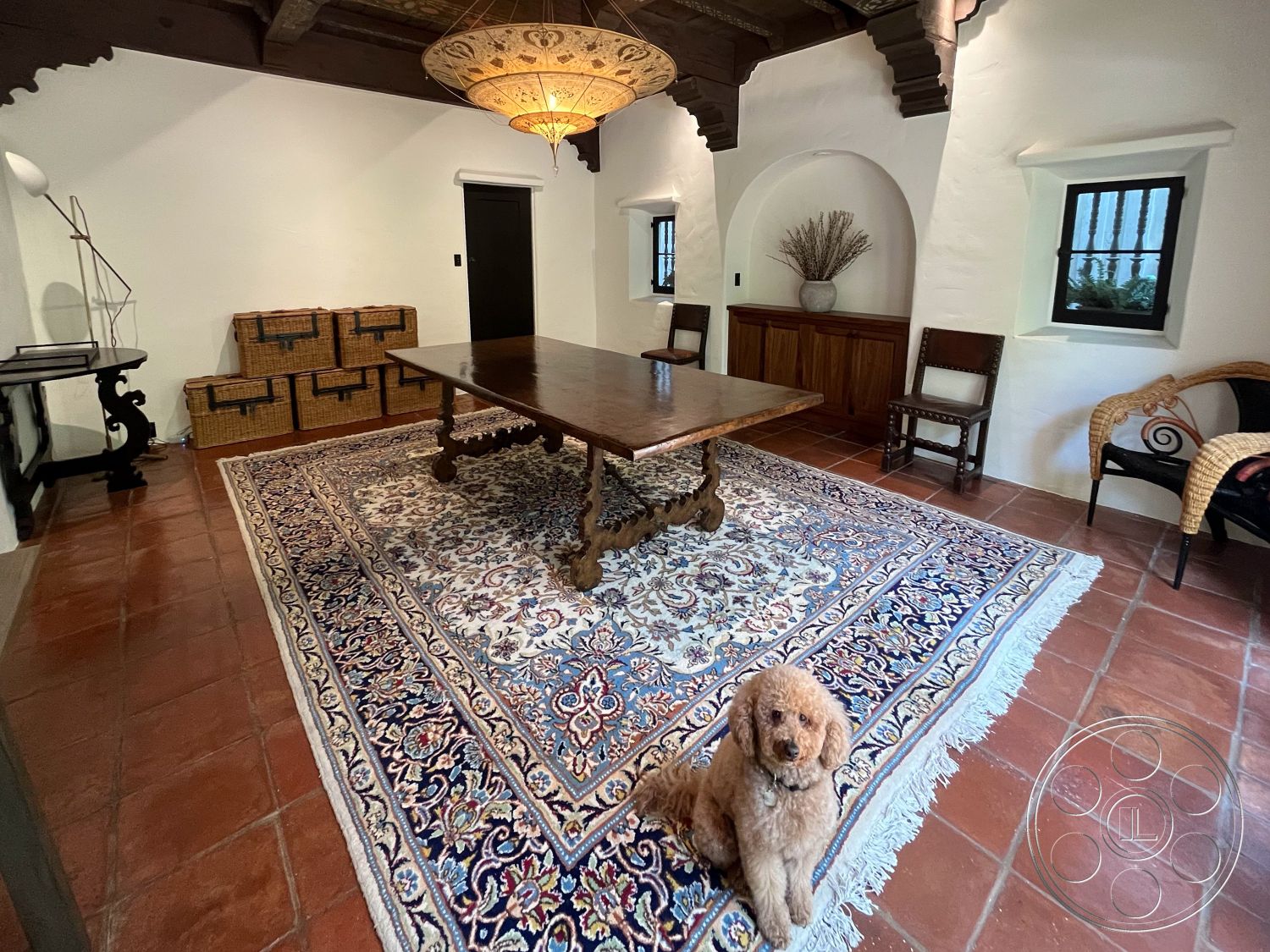 Medit 166 - textured plaster walls, decorative chandelier, arched windows, terracotta floor tiles, woven storage boxes, exposed wood ceiling beams, interior living space, neutral painted walls, wood beam ceiling, built-in wooden cabinetry, traditional Persian area rug, handcrafted wooden dining table, antique wicker chair, black iron window frames, rustic farmhouse style interior