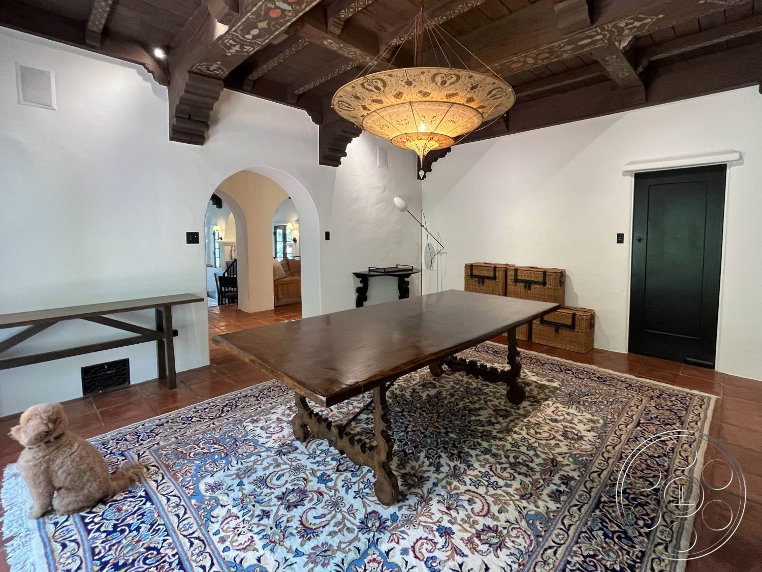 Medit 166 - arched doorways, terracotta tile flooring, open dining area, natural light from arched windows, traditional area rug, exposed wood beam ceiling, textured plaster interior walls, handcrafted wooden dining table, black painted wooden door, vintage-style chandelier, decorative wood ceiling panels, rustic side table, wicker storage boxes, Mediterranean interior style, cozy home atmosphere