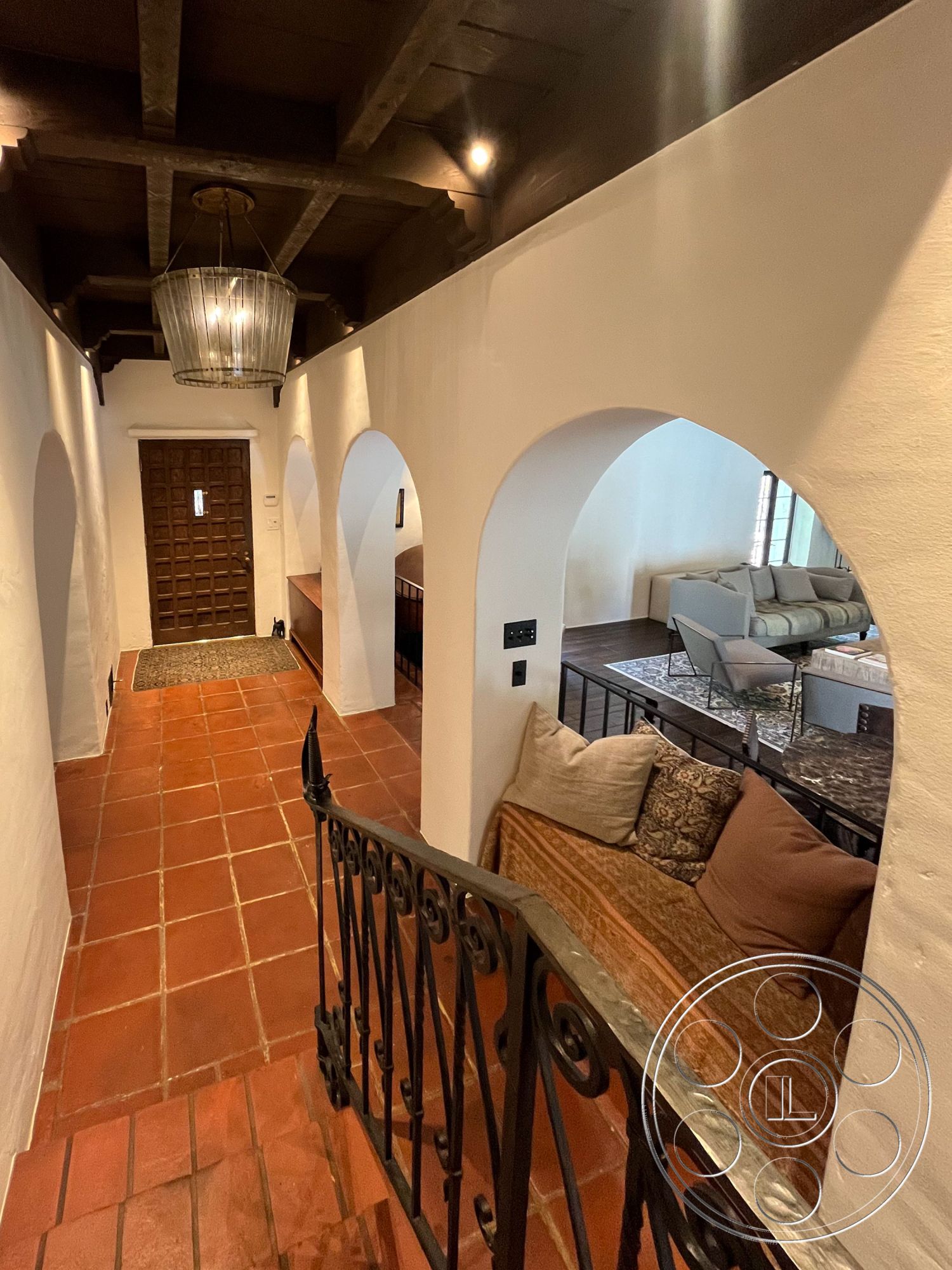 Medit 166 - open floor plan, cozy seating area, arched doorways, white plaster walls, earth-toned color palette, exposed wood ceiling beams, natural light through large windows, textured plaster wall treatment, interior hallway design, terra cotta tile flooring, iron railing staircase, traditional lantern pendant light, wooden entry door with paneling, modern living area layout, rustic charm interior