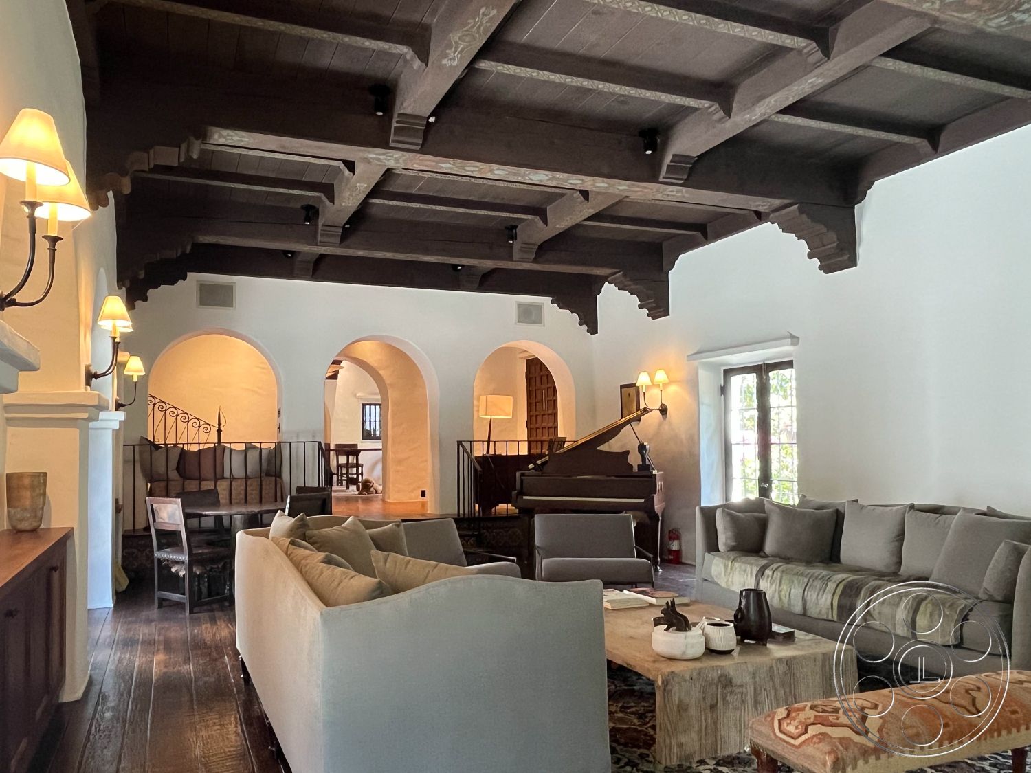 Medit 166 - decorative area rug, soft neutral color palette, round coffee table, open floor plan, cozy seating area, arched doorways, built-in cabinetry, dark wood ceiling beams, dining nook, exposed wood ceiling beams, hardwood living room floors, large window with natural light, modern sofa, white painted walls, textured fabric throw pillows, Ambient wall sconces, piano in living room, artisan wood dining table, traditional Spanish architecture