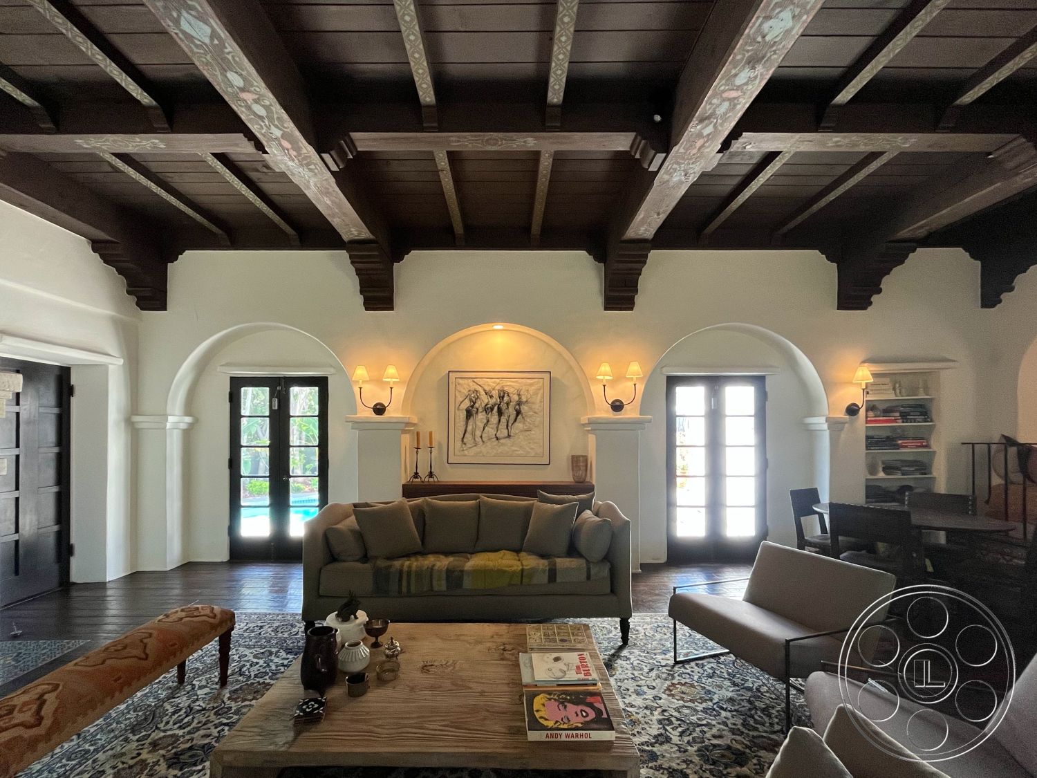 Medit 166 - interior vaulted ceiling with exposed wood beams, exterior arched doorways, interior built-in bookshelves, interior dark hardwood flooring, interior white plaster walls, interior traditional wooden furniture, interior rustic wood coffee table, interior decorative wall sconces, interior artwork on wall, interior cozy living room seating, interior stone fireplace surround, interior accent rug with intricate patterns, interior light-colored window treatments, interior dining area off living room