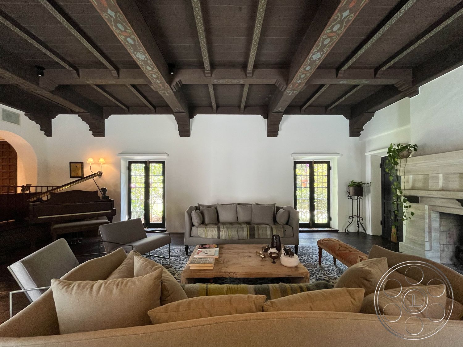 Medit 166 - neutral color palette, open floor plan, cozy seating area, textured plaster walls, large arched windows, exposed wood ceiling beams, natural light through windows, hardwood living room floors, interior living room, wood beam ceiling, traditional fireplace surround, accented wall paneling, built-in planter details, modern mid-century furniture, organic textures and fabrics, sophisticated country style