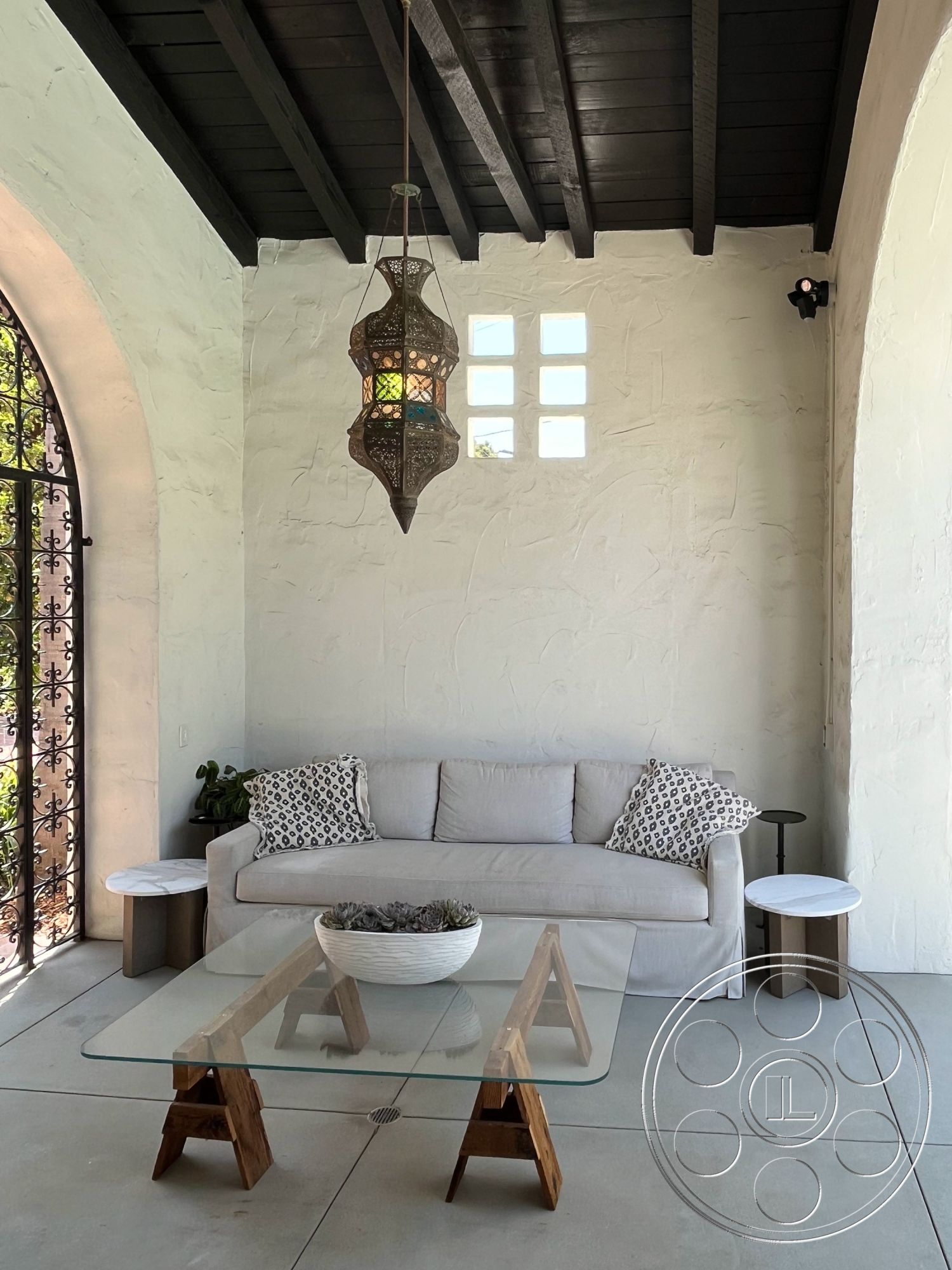 Medit 166 - exterior, glass coffee table, concrete flooring, outdoor lounge area, textured plaster walls, arched doorway, decorative throw pillows, stylish outdoor retreat, gray fabric sofa, modern outdoor furnishings, natural light interior, decorative wall lantern, minimalist outdoor seating, stucco wall treatment, wooden base coffee table, black wood ceiling beams, ornate pendant light fixture, potted succulent decor, elegant patio ambiance
