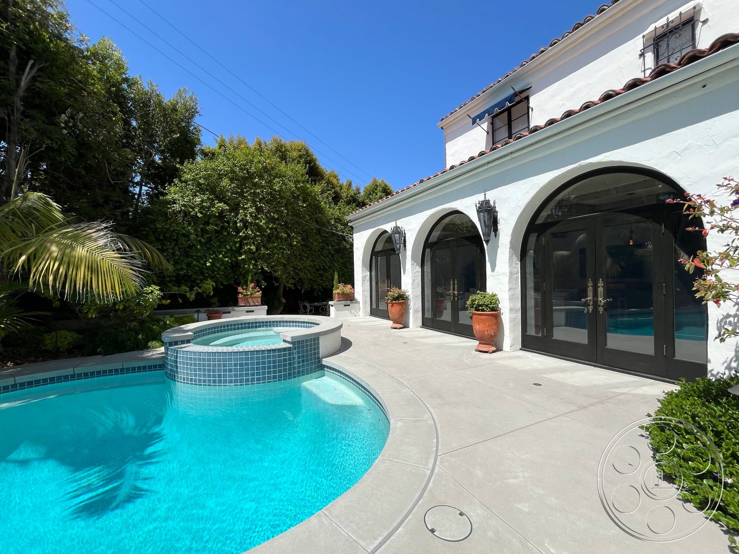 Medit 166 - exterior, outdoor seating area, arched doorways, Spanish tile roof, rectangular pool, white stucco wall, black framed glass doors, concrete patio flooring, landscaped garden setting, modern outdoor lighting fixtures, potted plant accents, tiled pool border