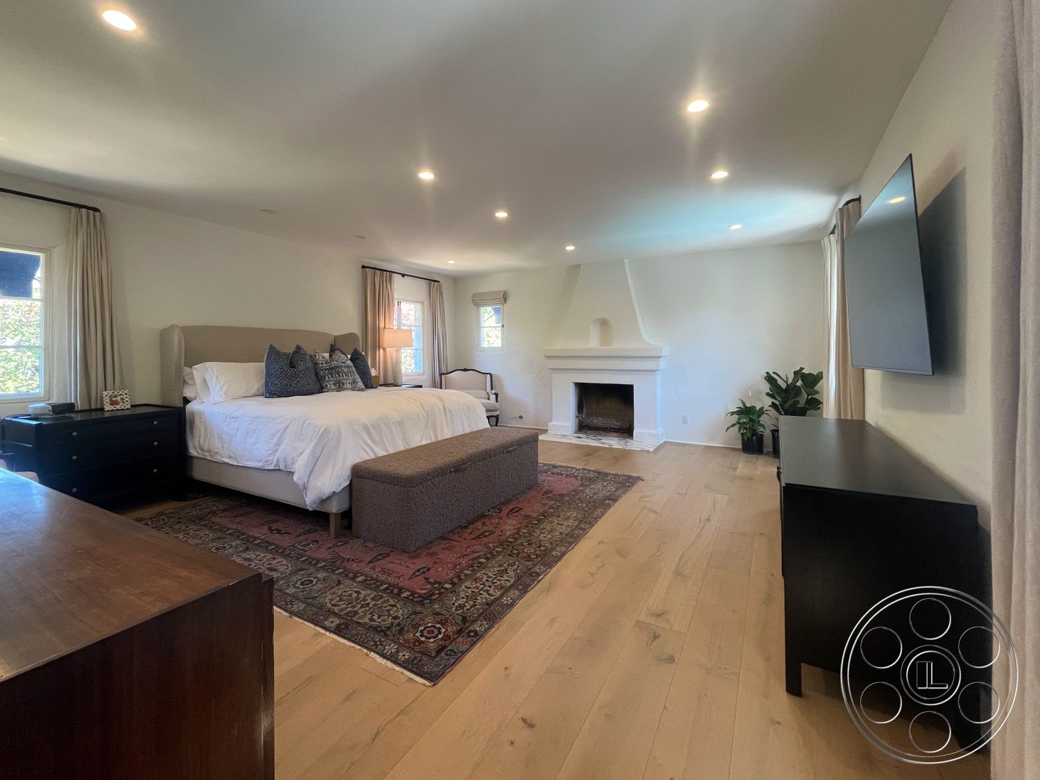 Medit 166 - neutral color palette, cozy reading nook, stylish area rug, textured ceiling details, exposed brick fireplace surround, hardwood bedroom floors, white painted walls, large windows with natural light, spacious master bedroom, modern king-size bed, elegant bedside lamps, minimalist wall-mounted TV, contemporary dresser, decorative plants for indoor ambiance